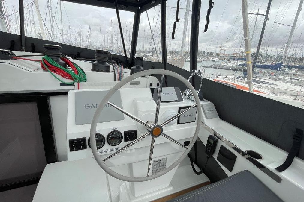 Helm of 2023 Fountaine Pajot Catamaran Aura 51 with navigation equipment and marina view.