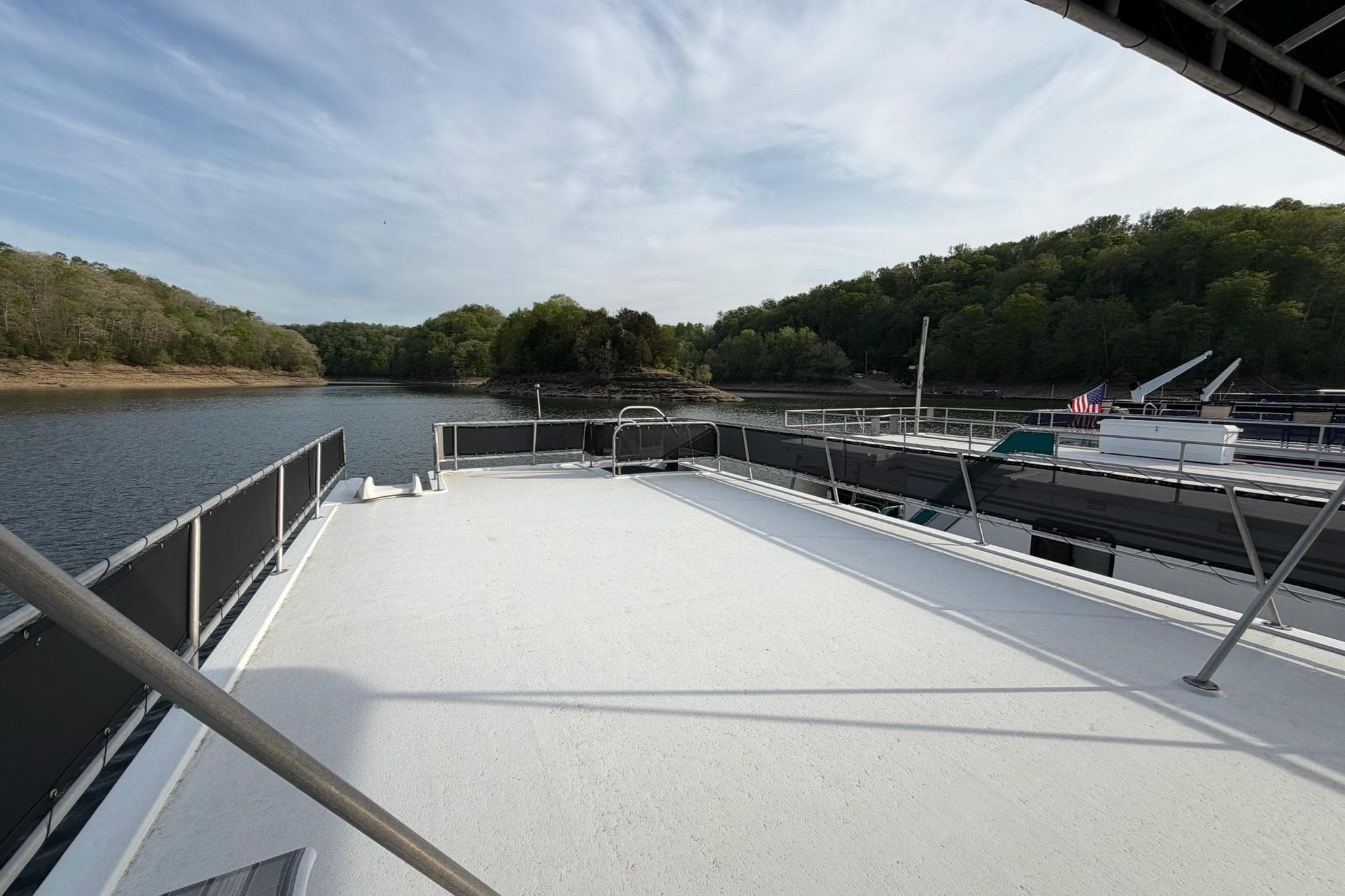 Sunstar 16x65 houseboat deck overlooking serene lake and lush green shoreline, 2000 model.