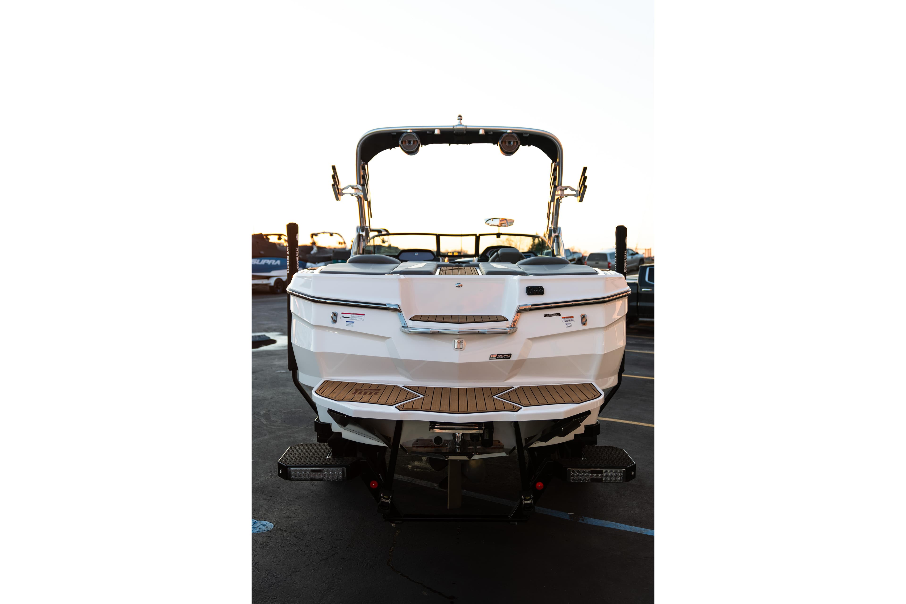 2022 MasterCraft XStar boat rear view with teak swim platform in a parking lot.