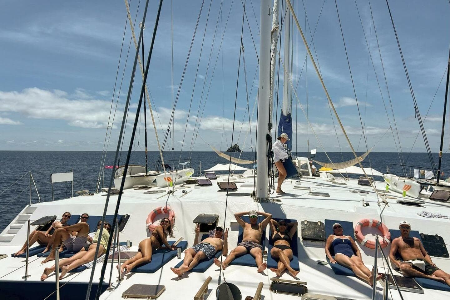 People relaxing on a 1987 Custom Trimaran sailboat under clear skies.