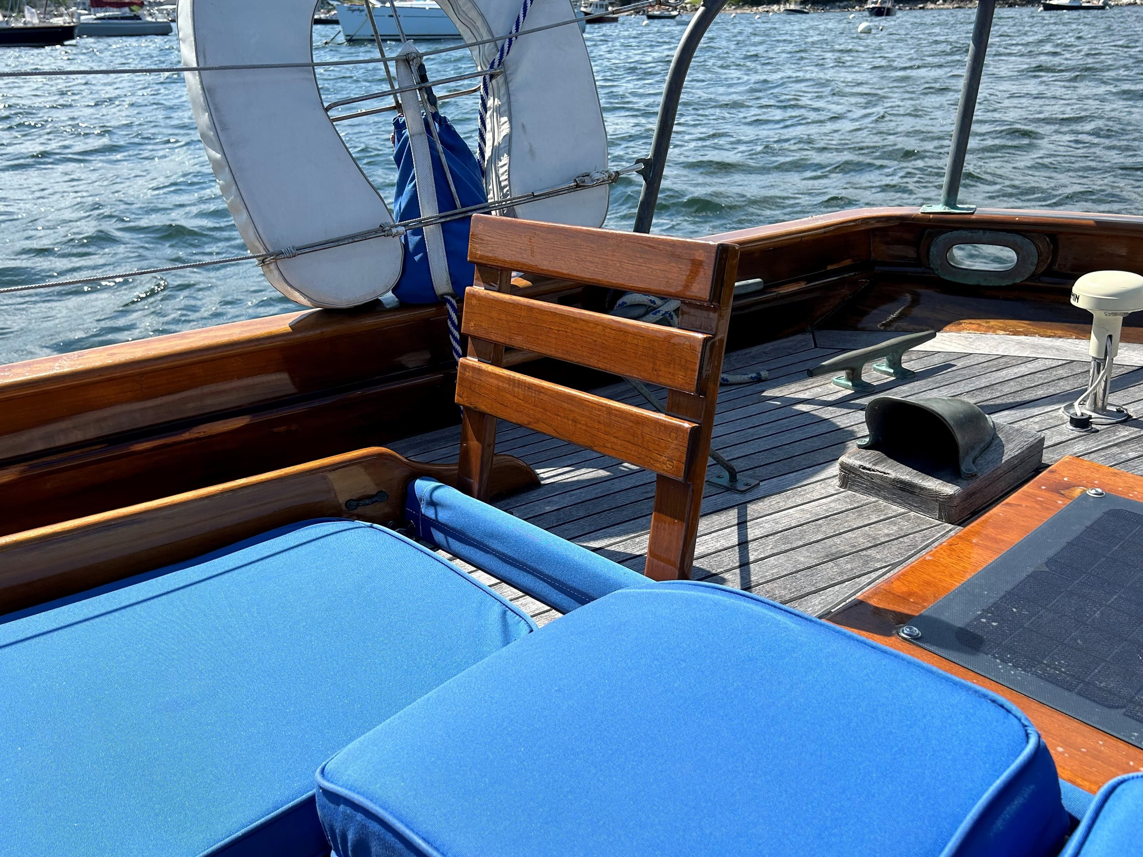 1985 Herreshoff Nereia Molly's Cove 38' sailboat deck with blue cushions and wooden seating.