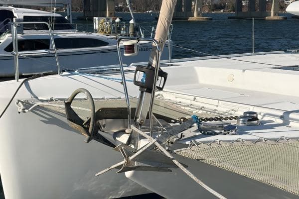 Bow of 2008 Lagoon 420 catamaran with anchor and netting, docked in marina.