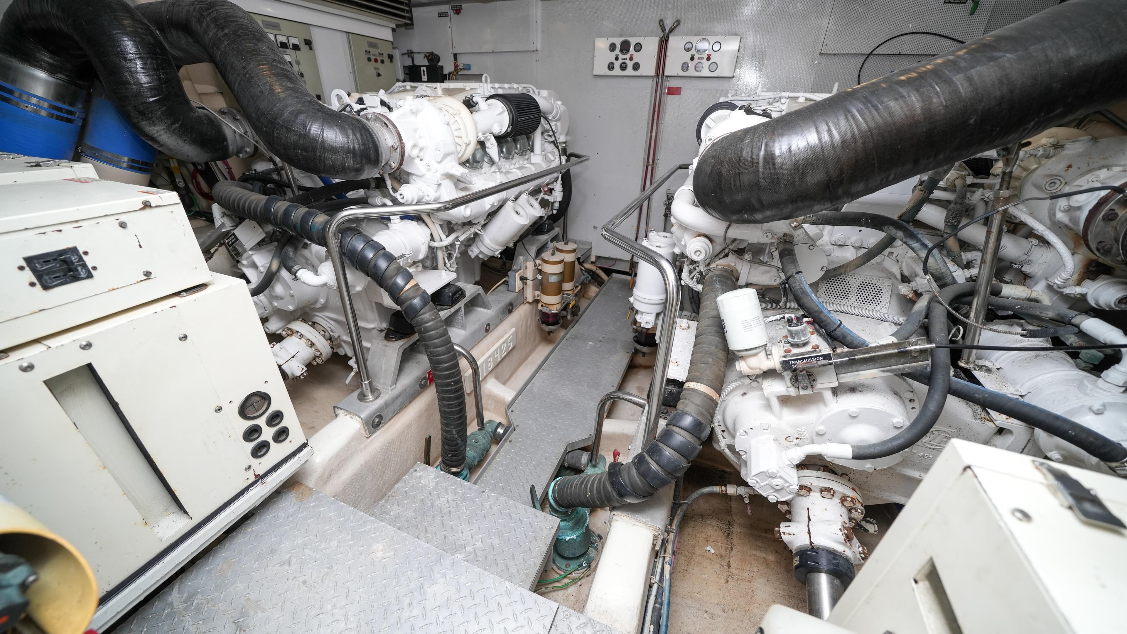 Engine room of a 2002 Queenship 70 Baretta yacht with dual engines and control panels.
