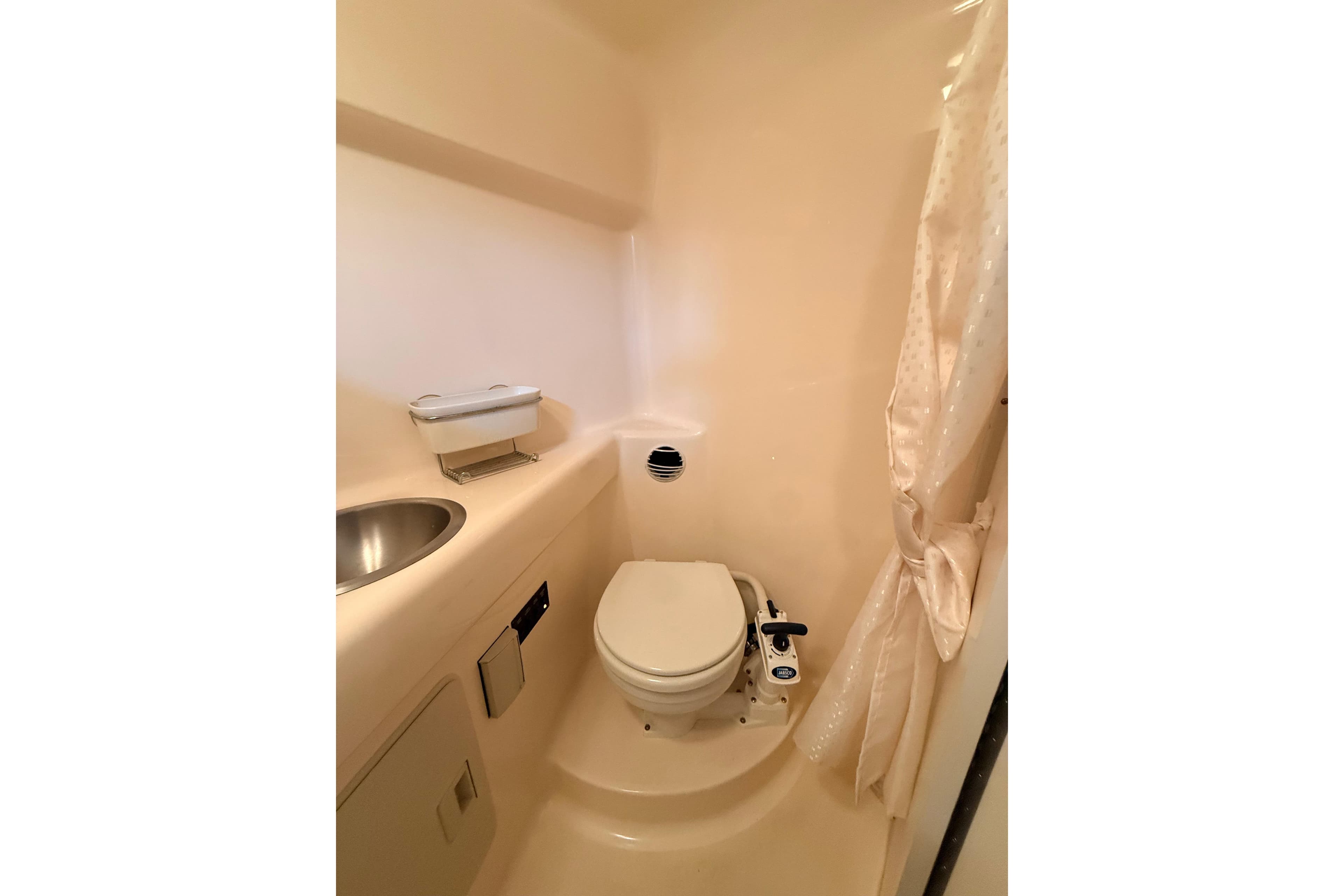 2007 Glastron GS 279 boat bathroom with toilet, sink, and shower curtain.