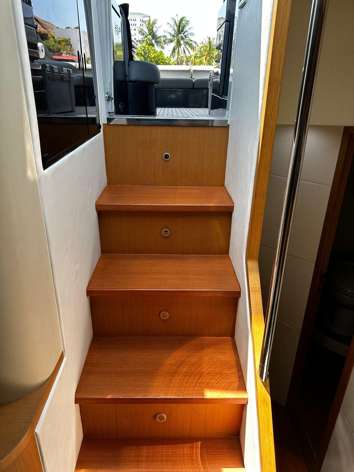 Staircase inside 2009 Pershing 56 yacht, leading to upper deck with outdoor view.