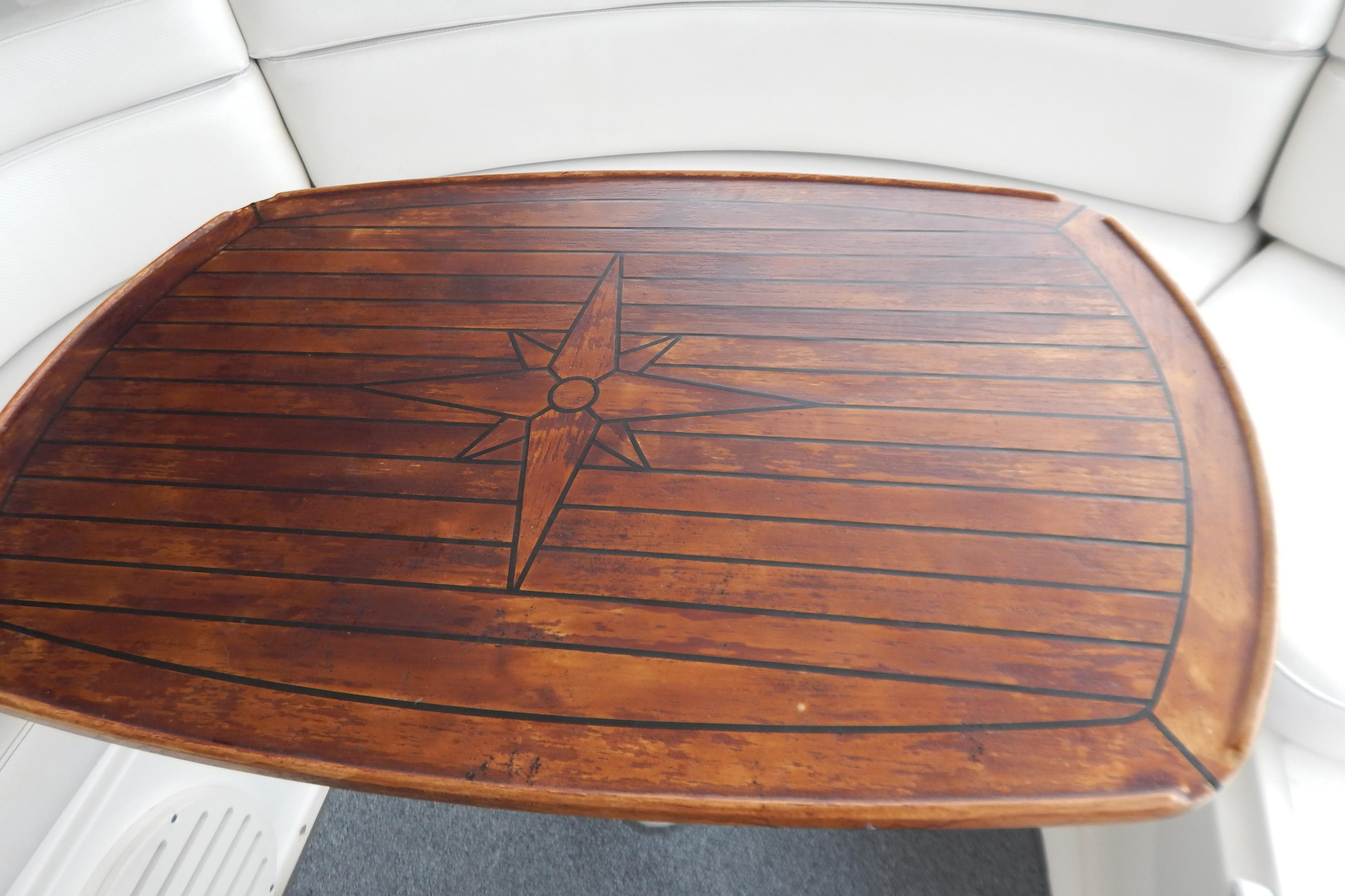 Wooden table with compass design on a 2004 Regal Commodore 4260 boat.