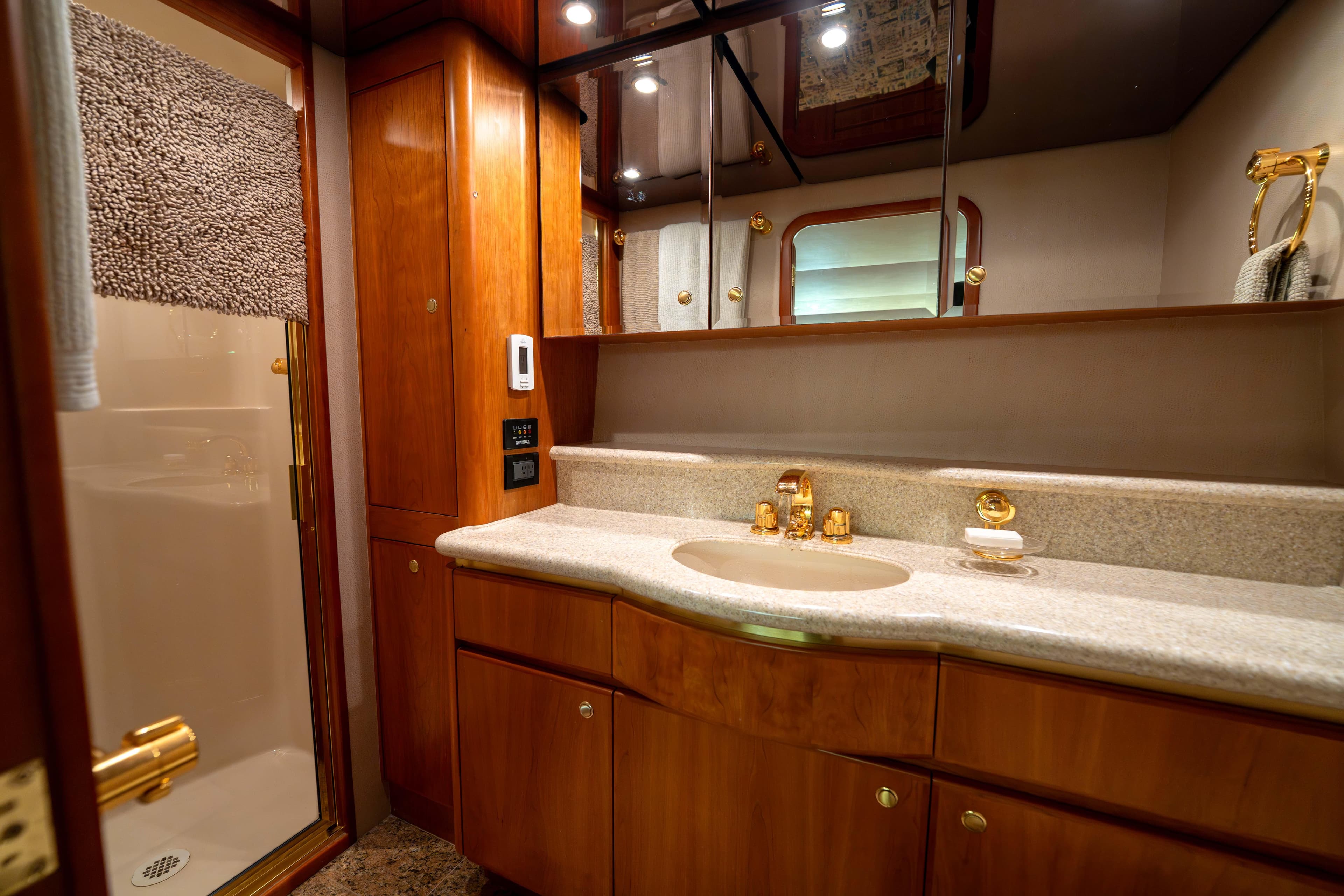 Luxurious bathroom in 2001 West Bay 58 RPH yacht with wood cabinetry and gold fixtures.