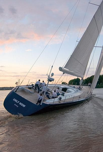 Sailing yacht CNB 104, 2002 model, cruising at sunset on calm waters.