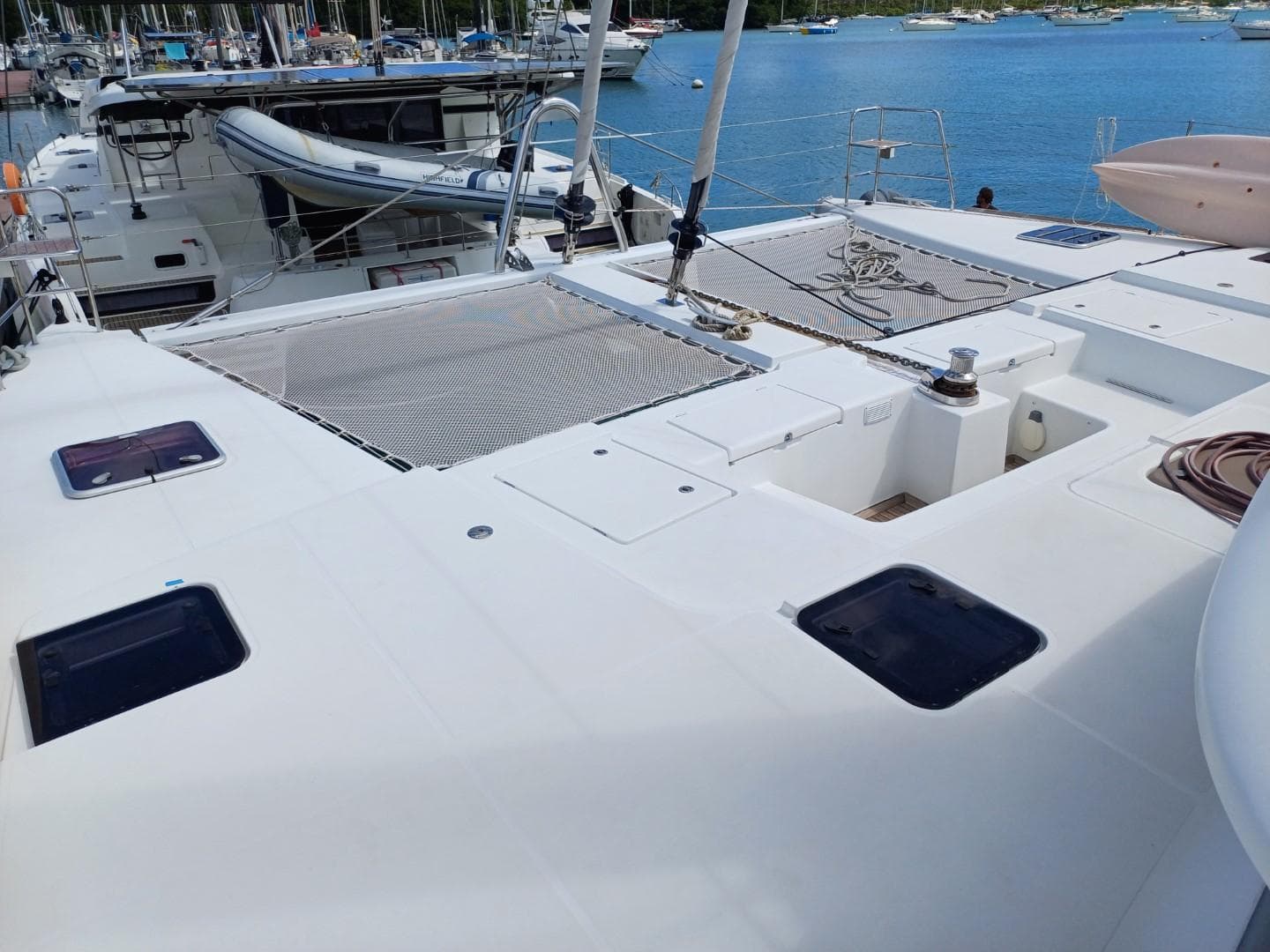 2012 Lagoon 560 catamaran deck with netting, docked in a marina.