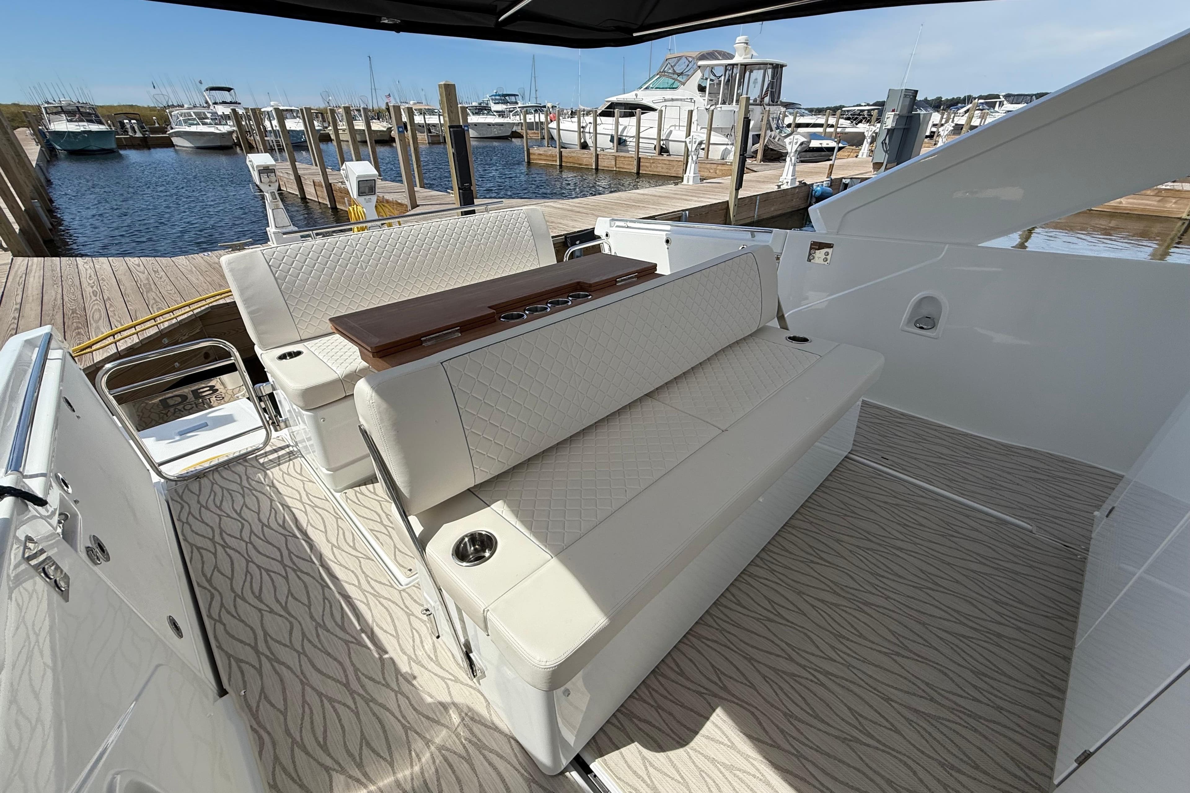 2026 Jeanneau DB/37 OB boat interior with elegant seating at a marina dock.