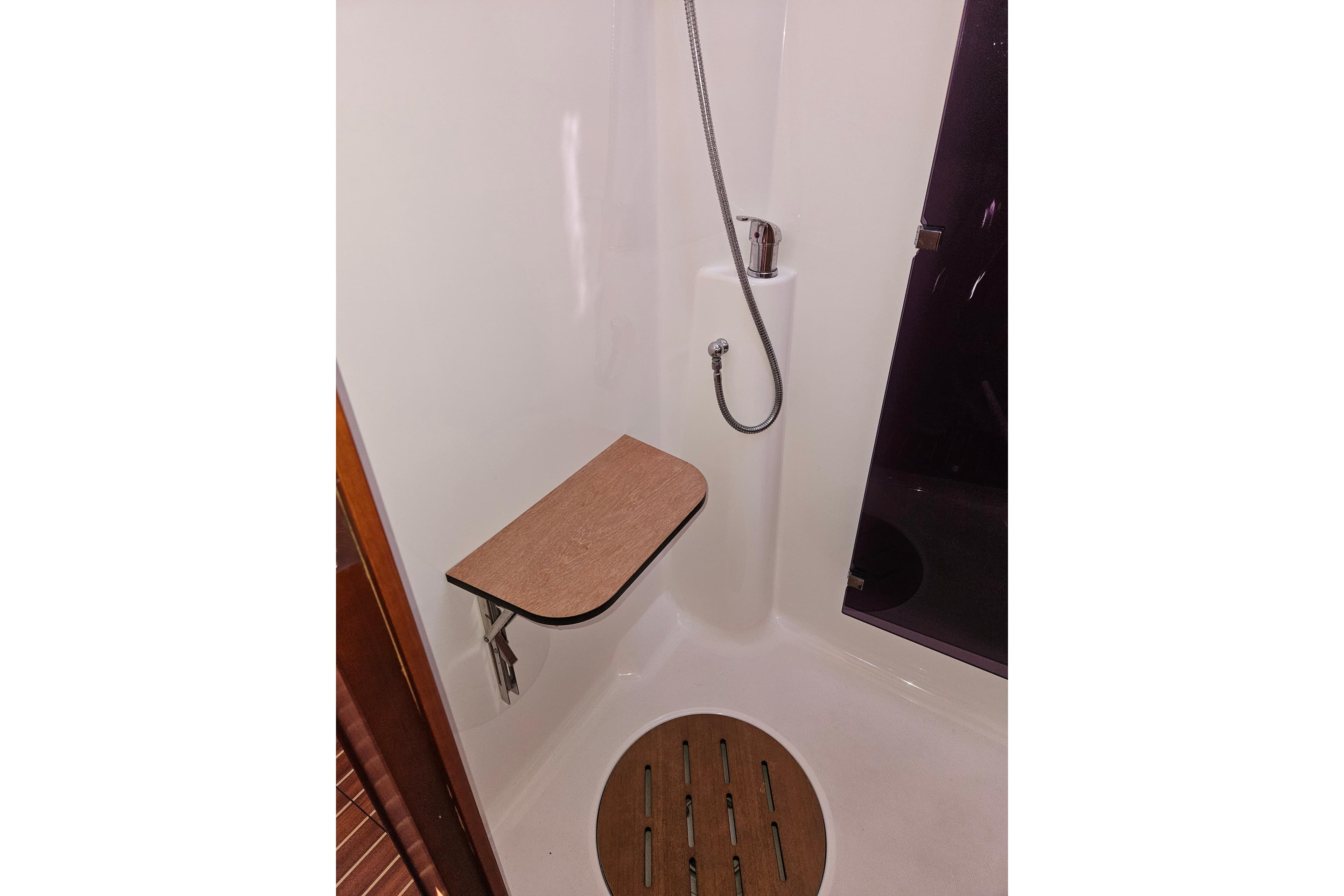Shower area in 2018 Dufour 460 Grand Large yacht with foldable seat and handheld showerhead.