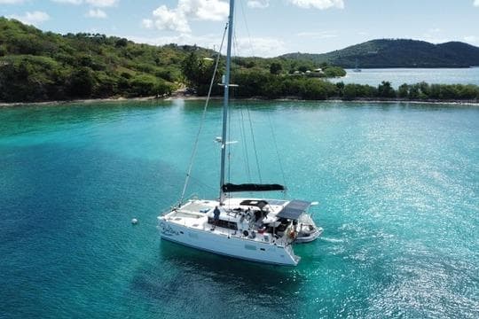 2018 Lagoon 400 S2 catamaran anchored in clear turquoise waters near lush green island.