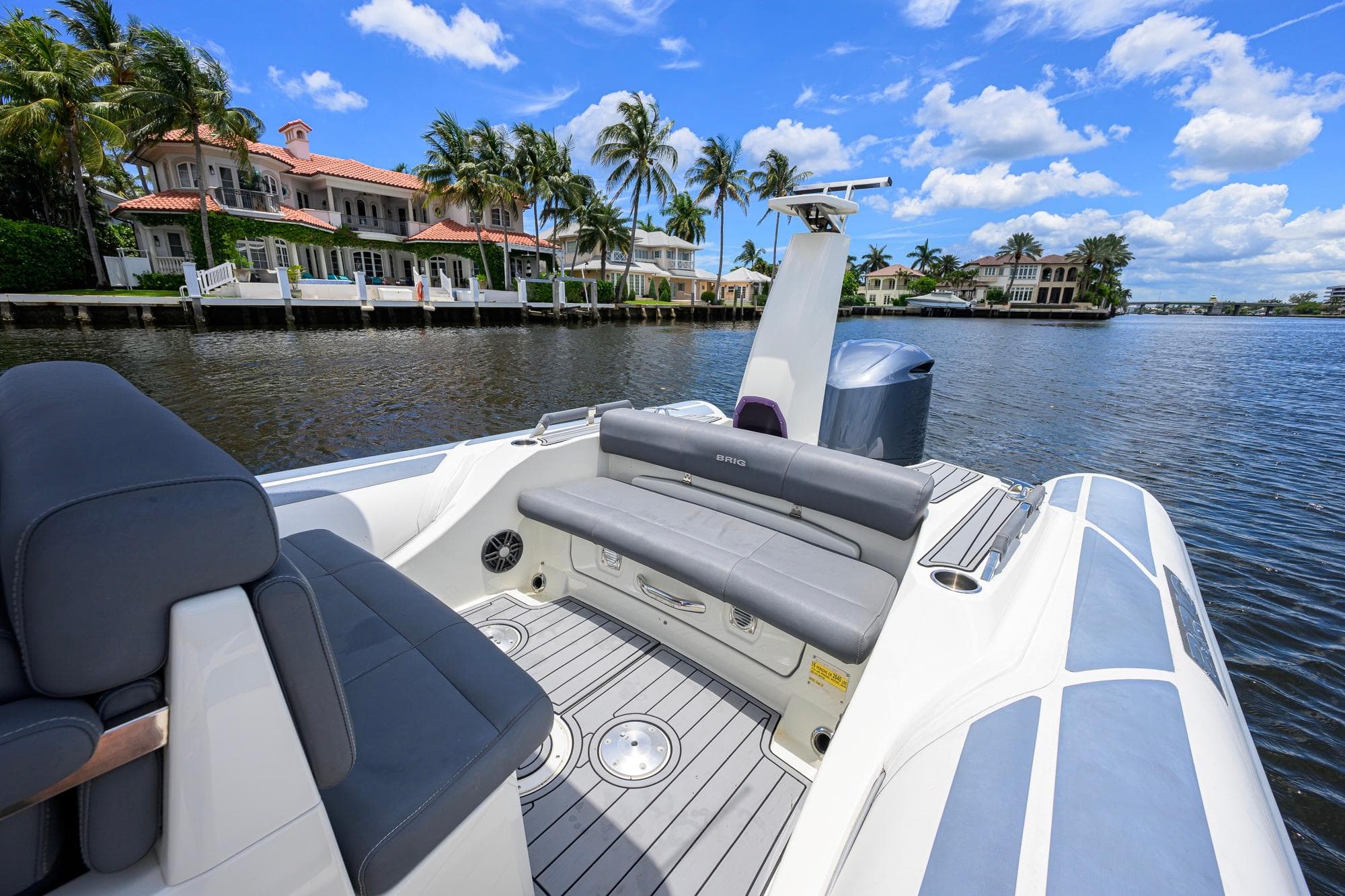2021 Brig Eagle 8 boat on a scenic waterfront with luxury homes and palm trees.