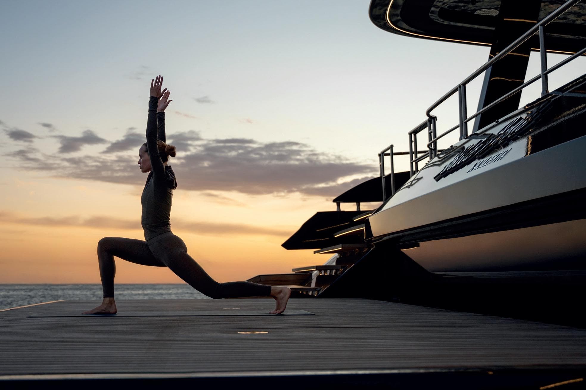 Woman practicing yoga on Sunreef 70 NEXT yacht at sunset, 2027 model.
