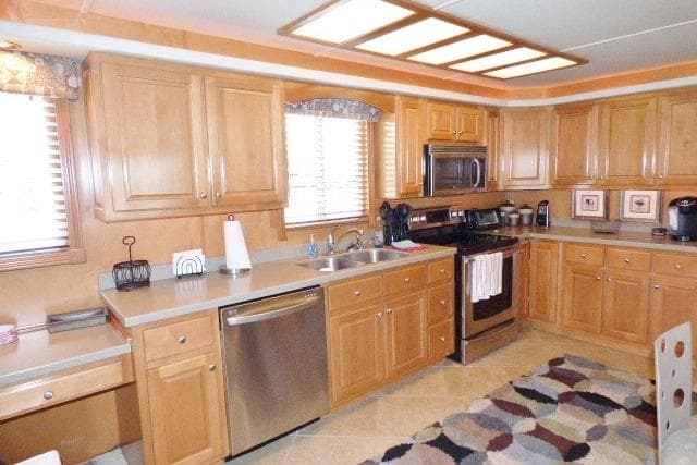 Spacious kitchen with wooden cabinets, stainless steel appliances, and patterned rug, in a 2007 Starlite 18x85.