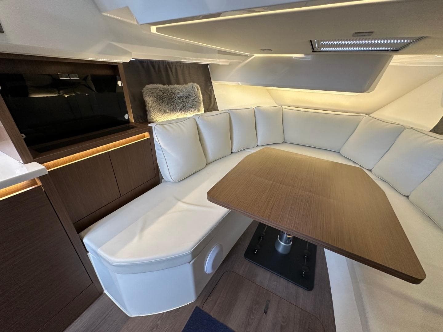 Luxurious interior of 2022 Jeanneau Leader 12.5 WA with plush seating and wooden table.