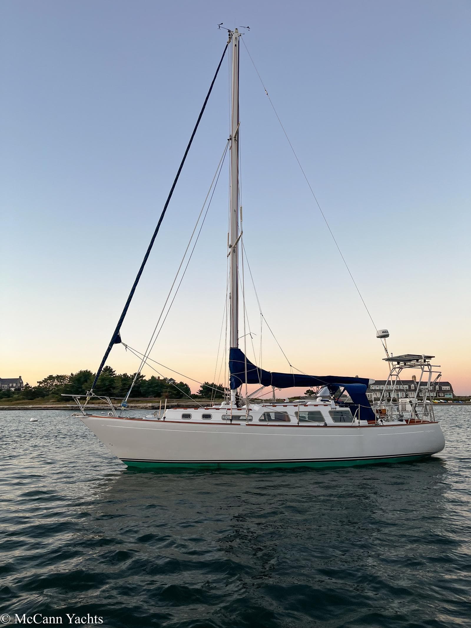 1973 Challenger 40 sailboat on calm water at sunset.