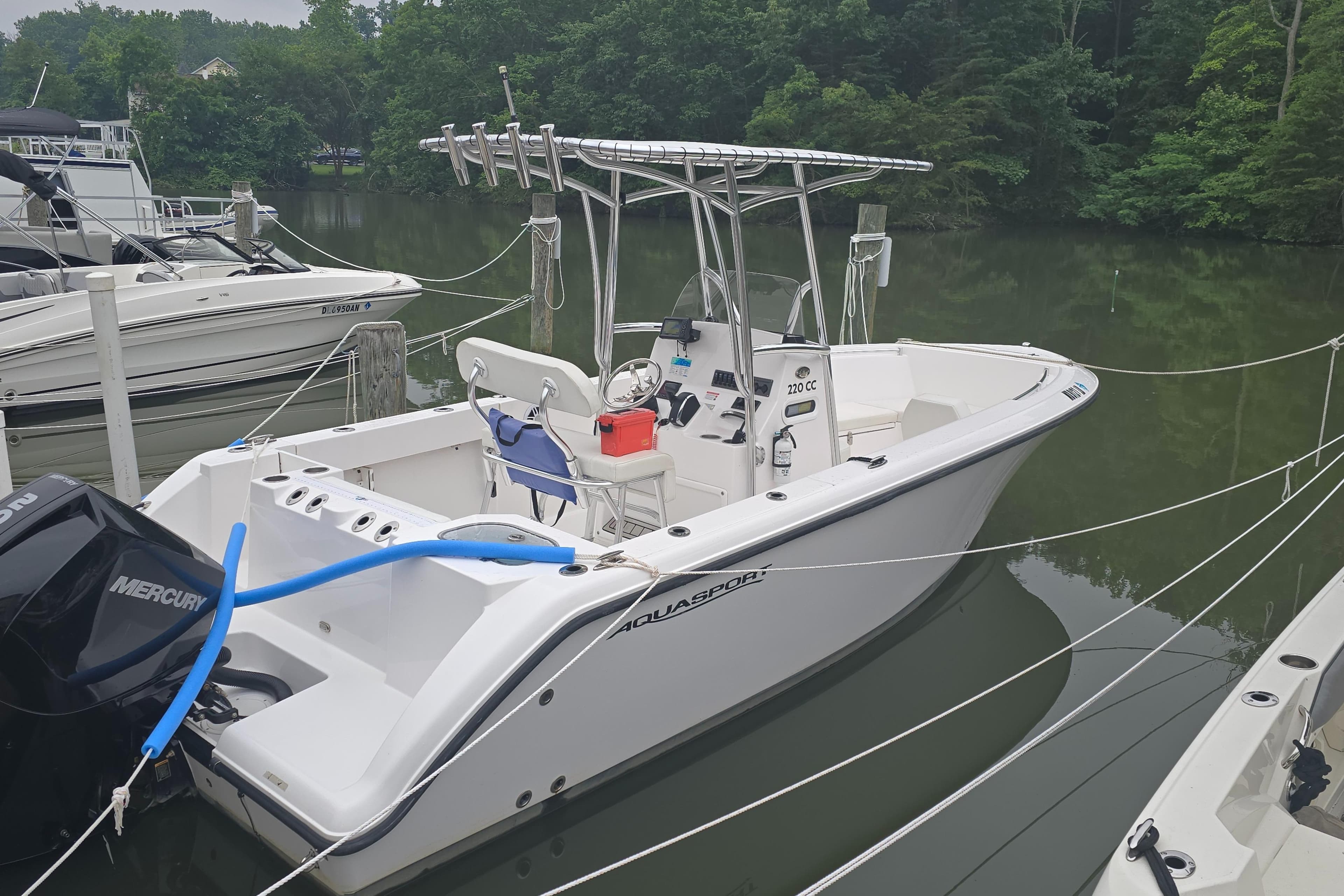 2024 Aquasport 2200 Center Console boat docked on a calm lake.