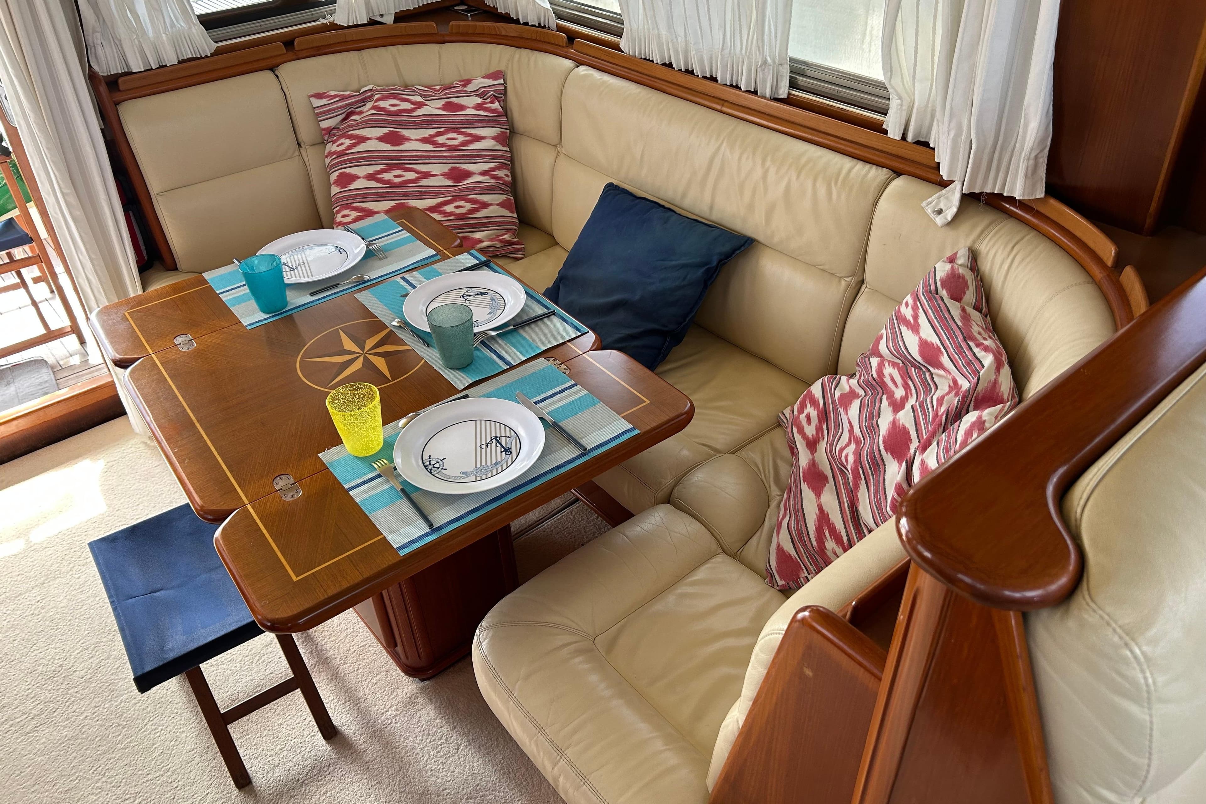 Interior of 2004 Belliure 40 yacht with dining area, cushioned seating, and nautical-themed table.