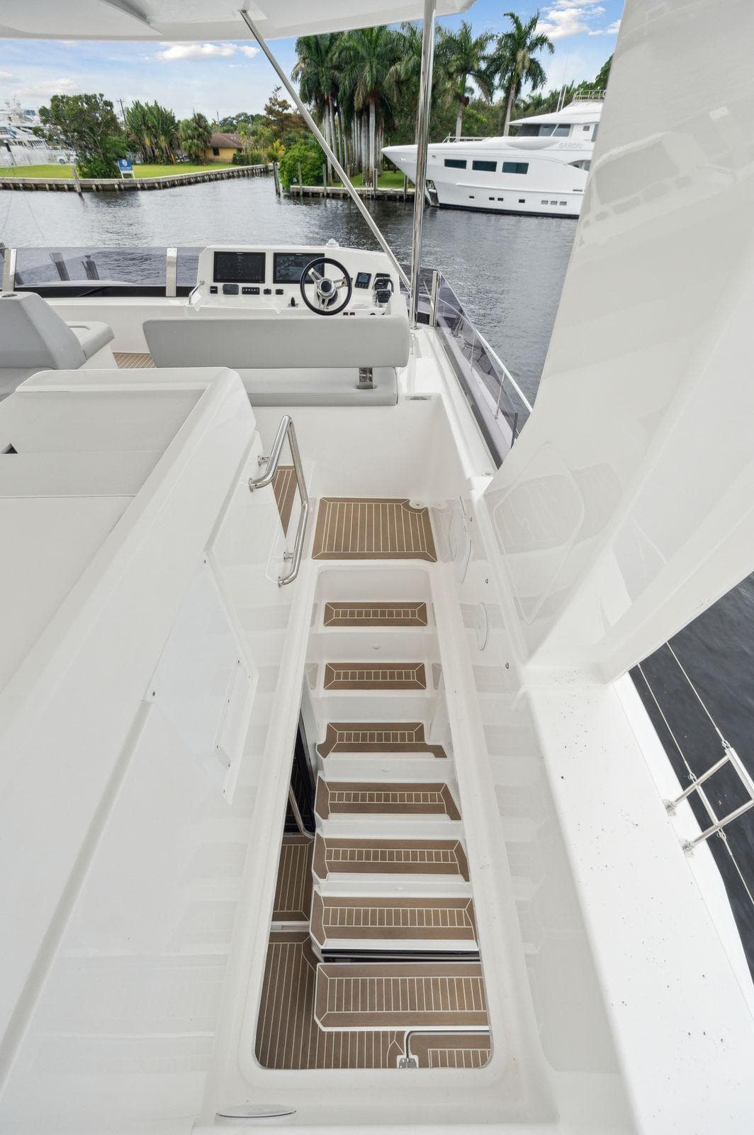 2024 Leopard 53 Powercat yacht with modern deck and helm, docked near lush greenery.