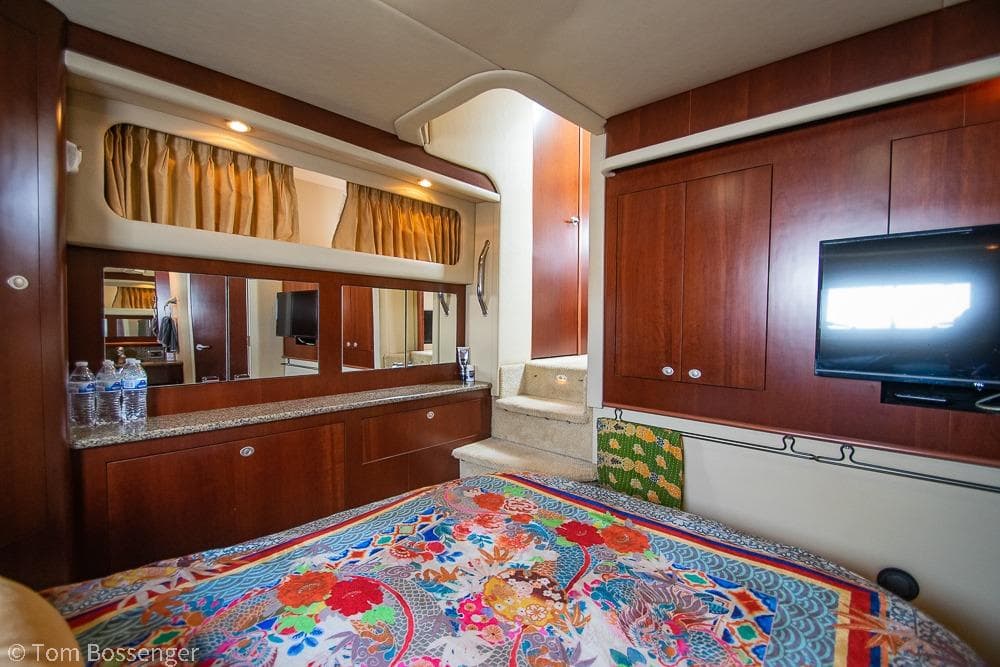 Luxurious 2005 Sea Ray 390 Motor Yacht interior with vibrant bedding and elegant wood cabinetry.