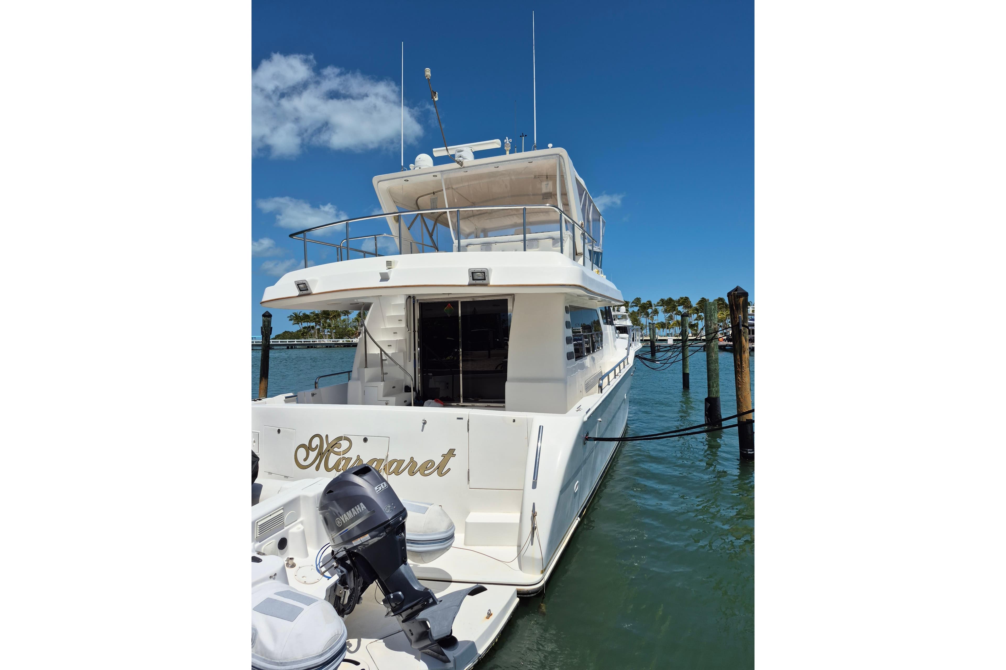 2006 Altima Flybridge yacht docked at marina, clear sky, calm water.