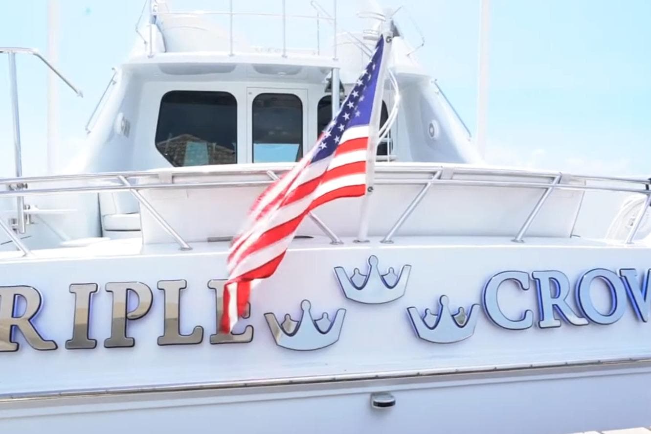 1987 Magnum 70 Convertible yacht with American flag and "Triple Crown" text.