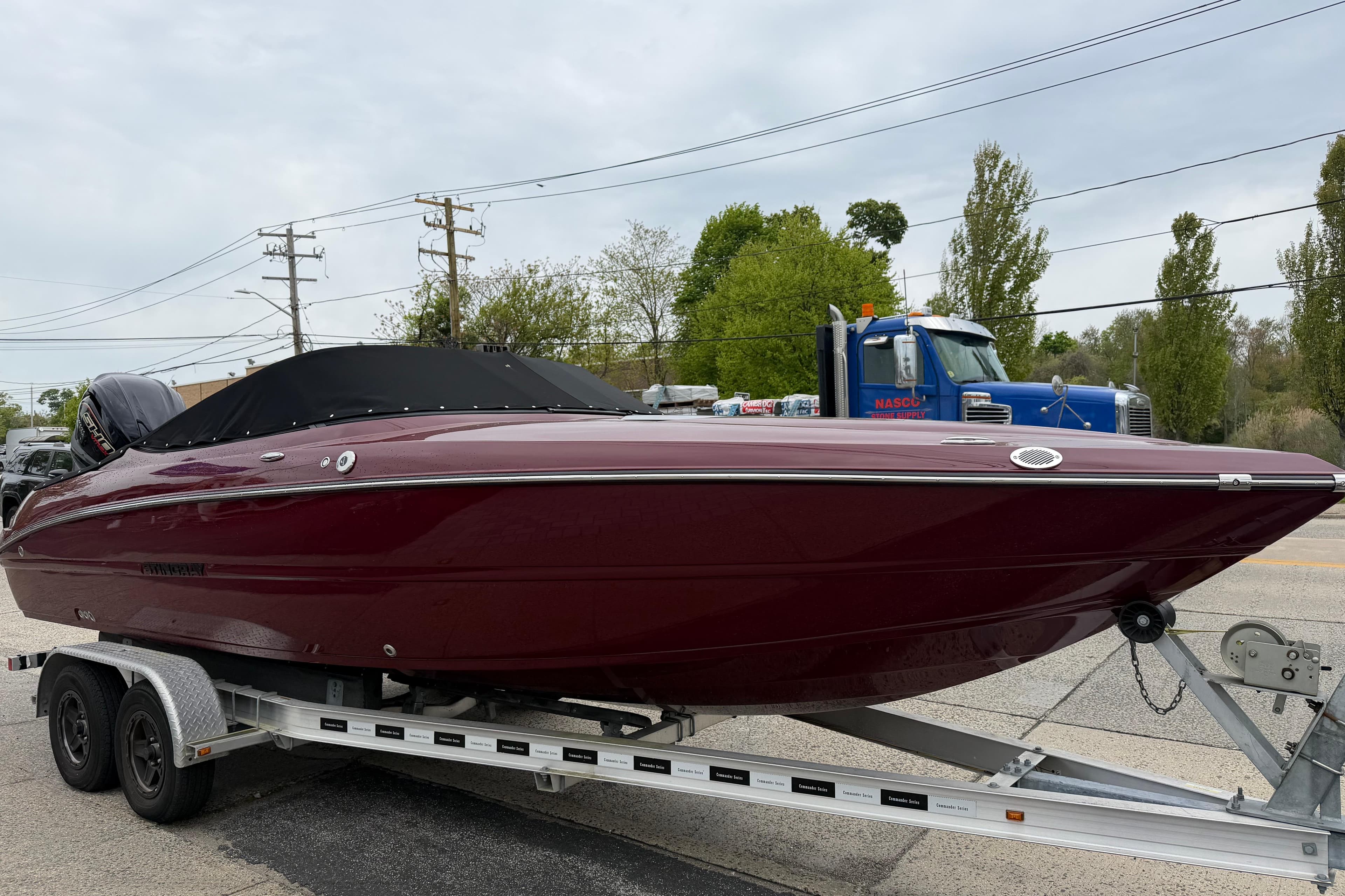 2026 Stingray 23 OCX boat on trailer, maroon color, parked outdoors.