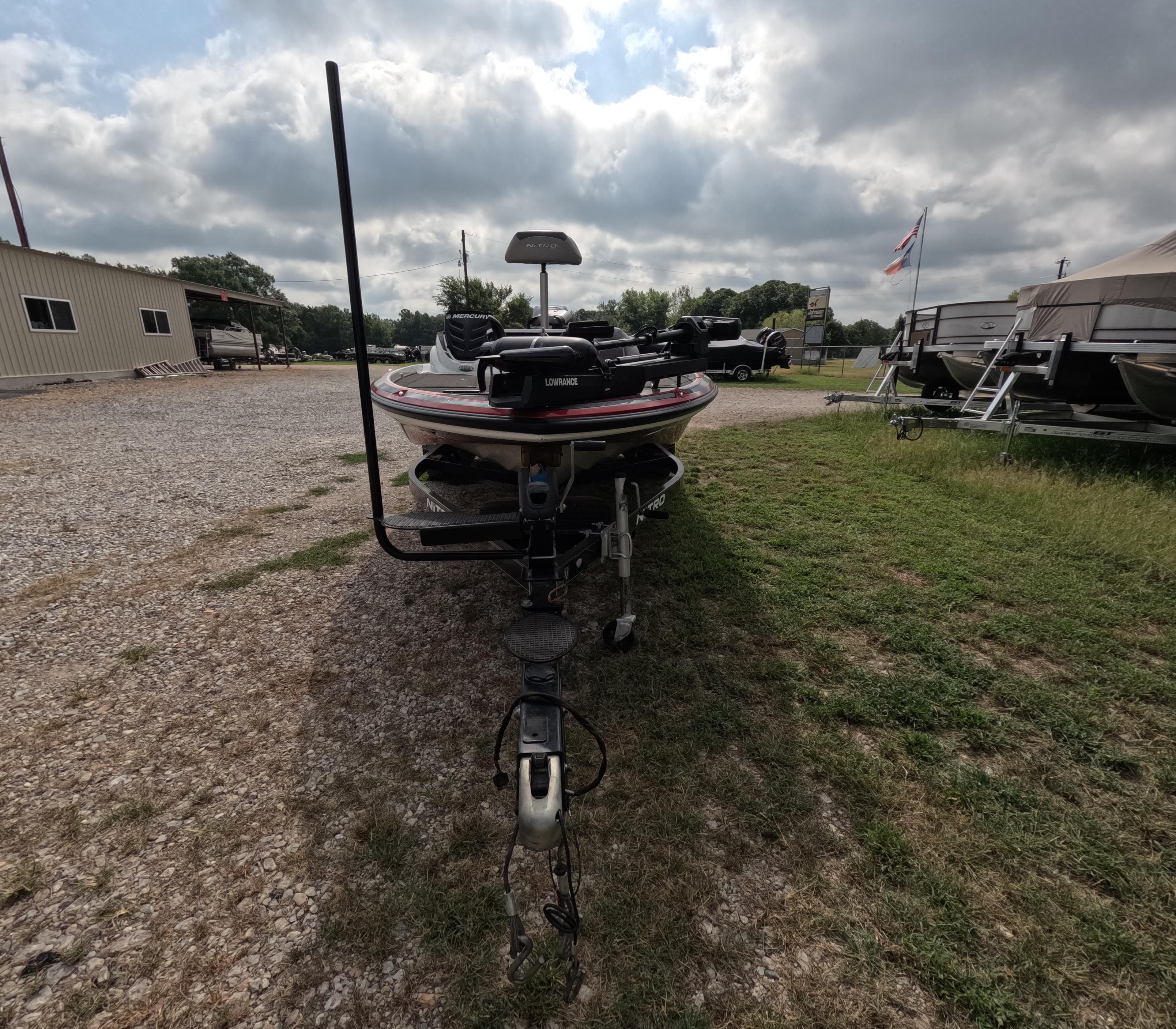 2016 Nitro Z20 boat on trailer, parked on gravel and grass under cloudy sky.