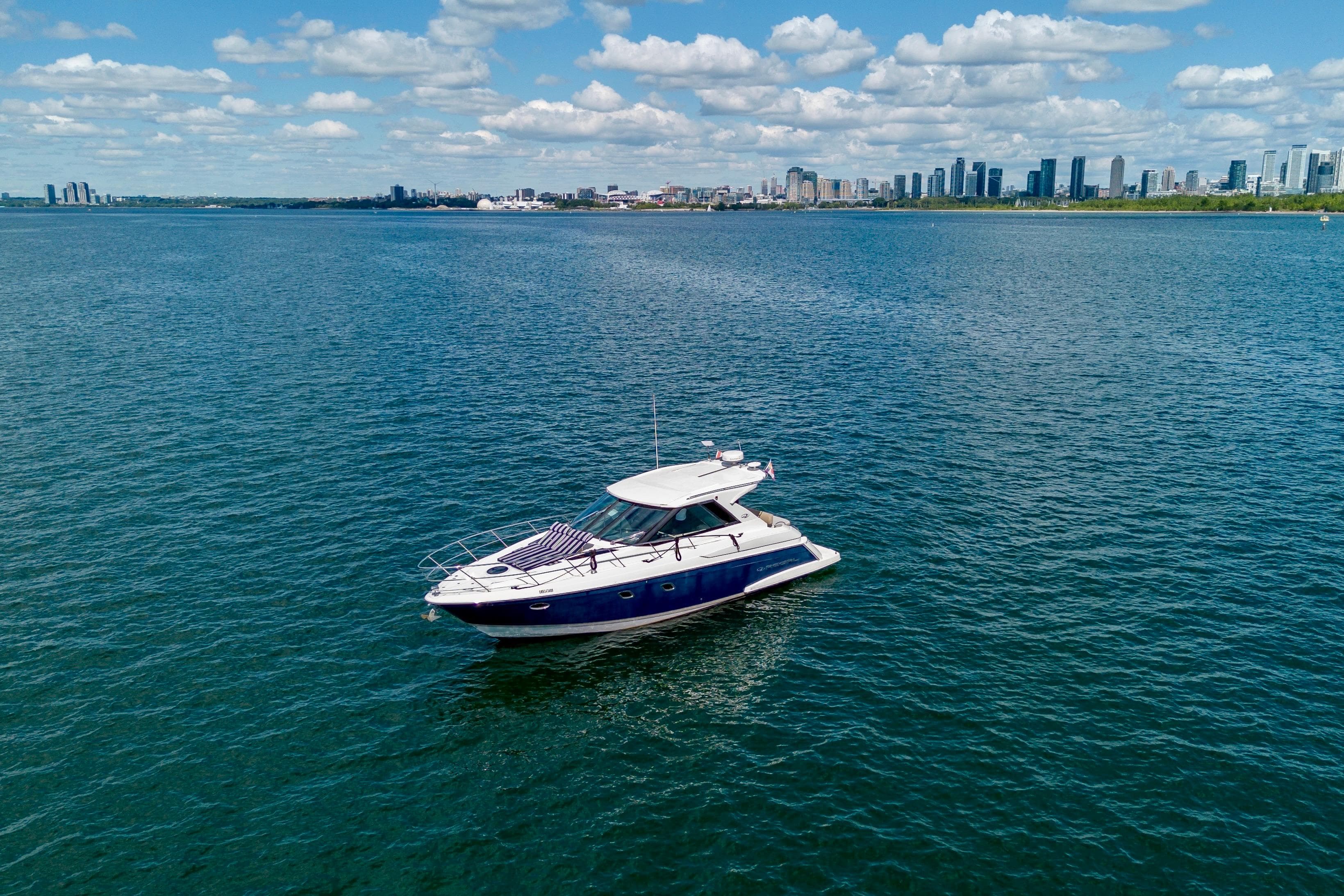 2012 Regal 42 Sport Coupe yacht on open water with city skyline in background.