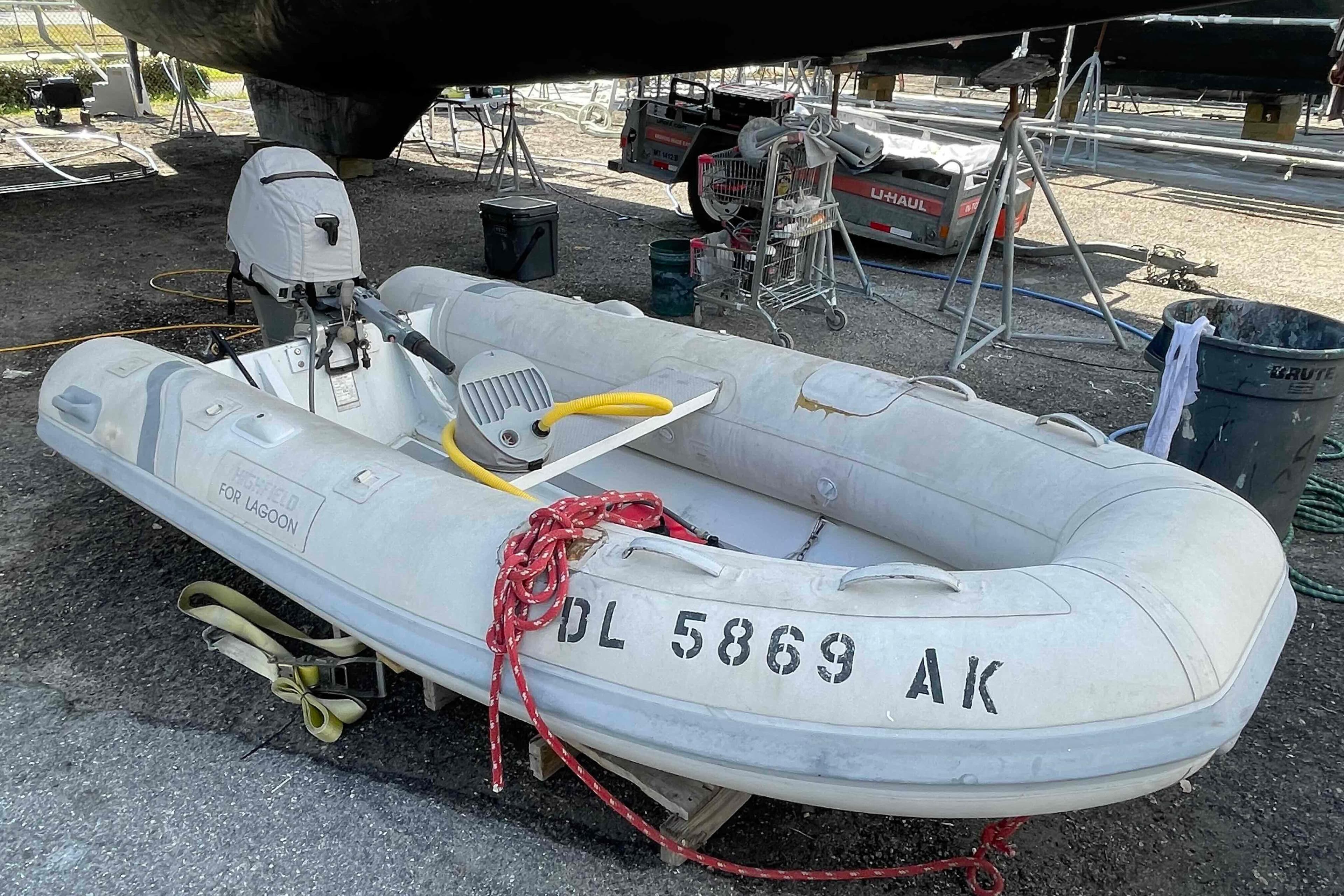 Inflatable dinghy with outboard motor, labeled "For Lagoon," parked on a boatyard.