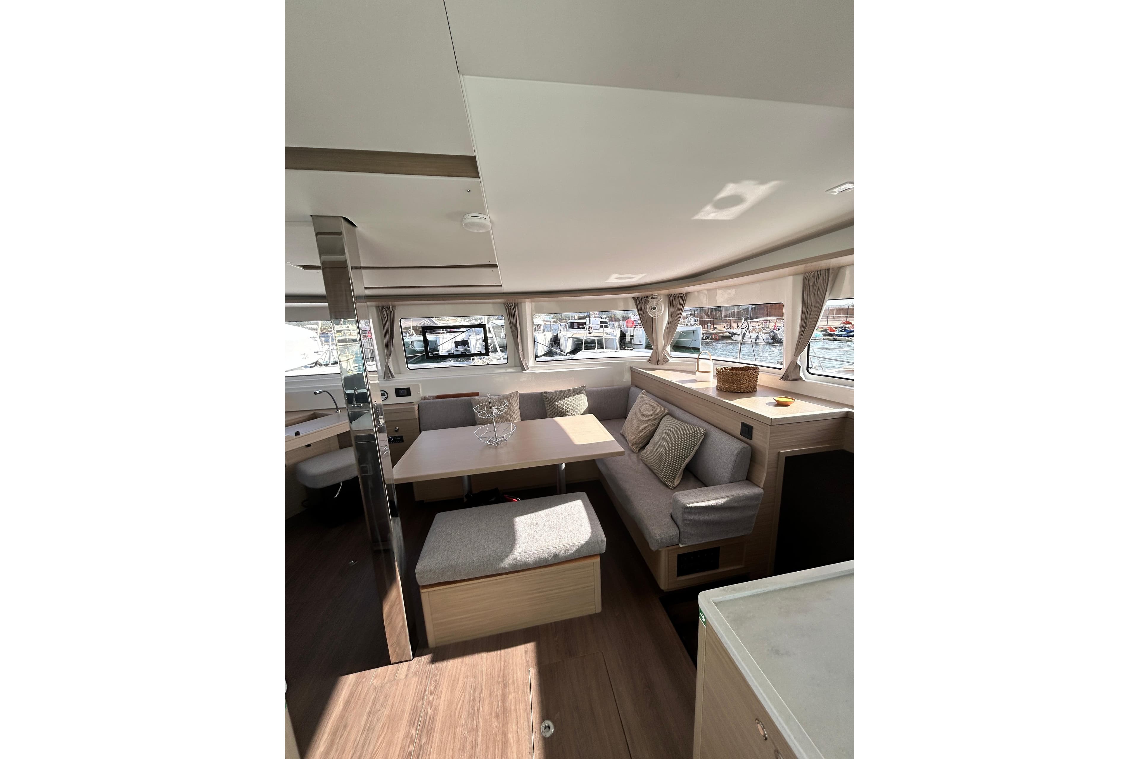 Interior of 2024 Lagoon 46 catamaran, featuring modern seating and large windows.