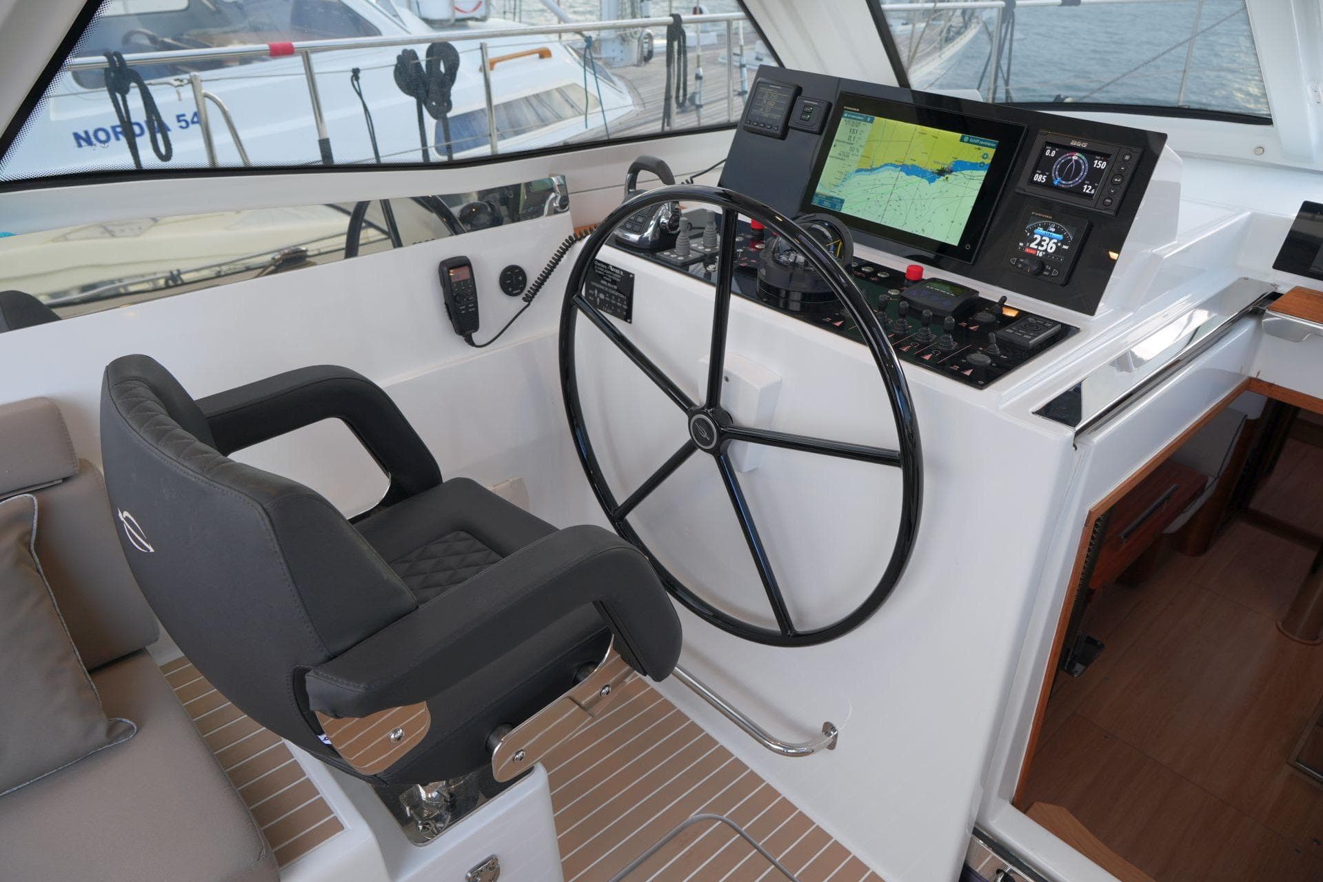 Modern helm station of 2023 Amel 50 yacht with navigation equipment and steering wheel.