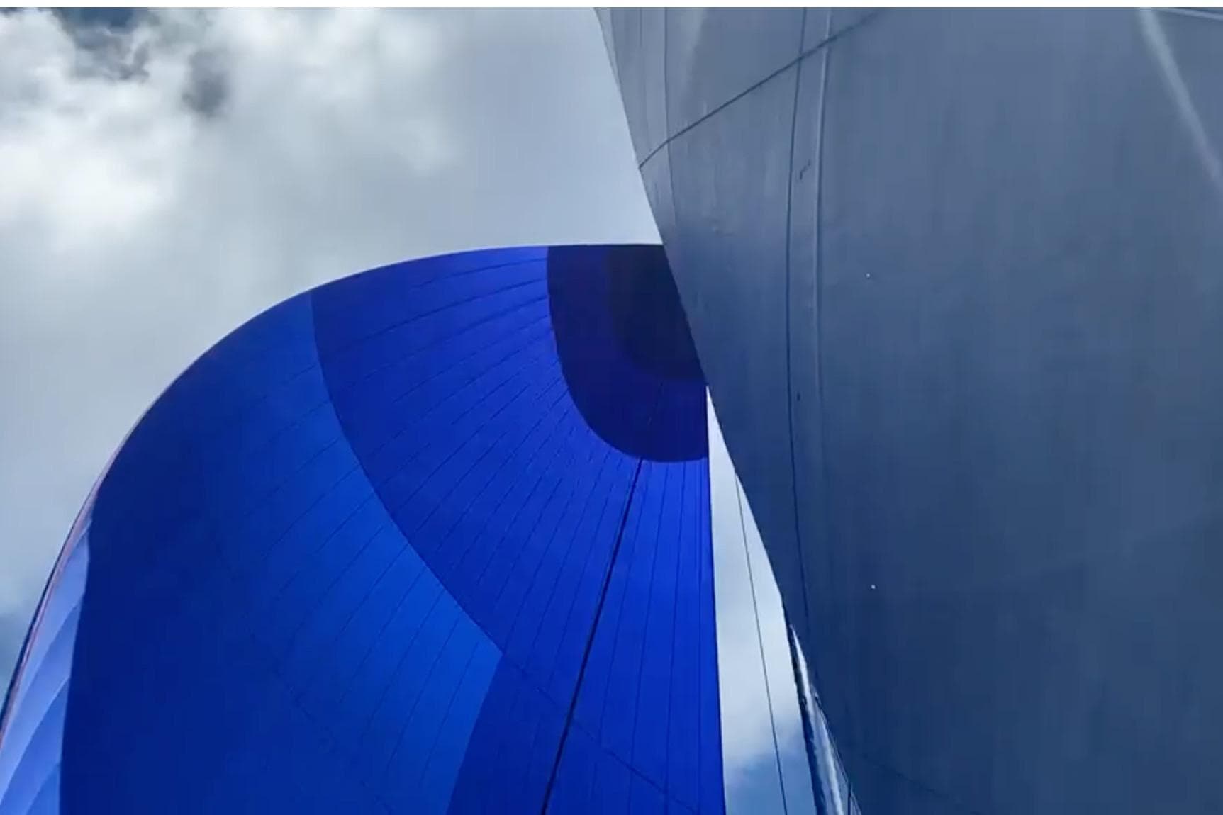 Blue sail of a 2003 Catana 582 yacht against a cloudy sky.
