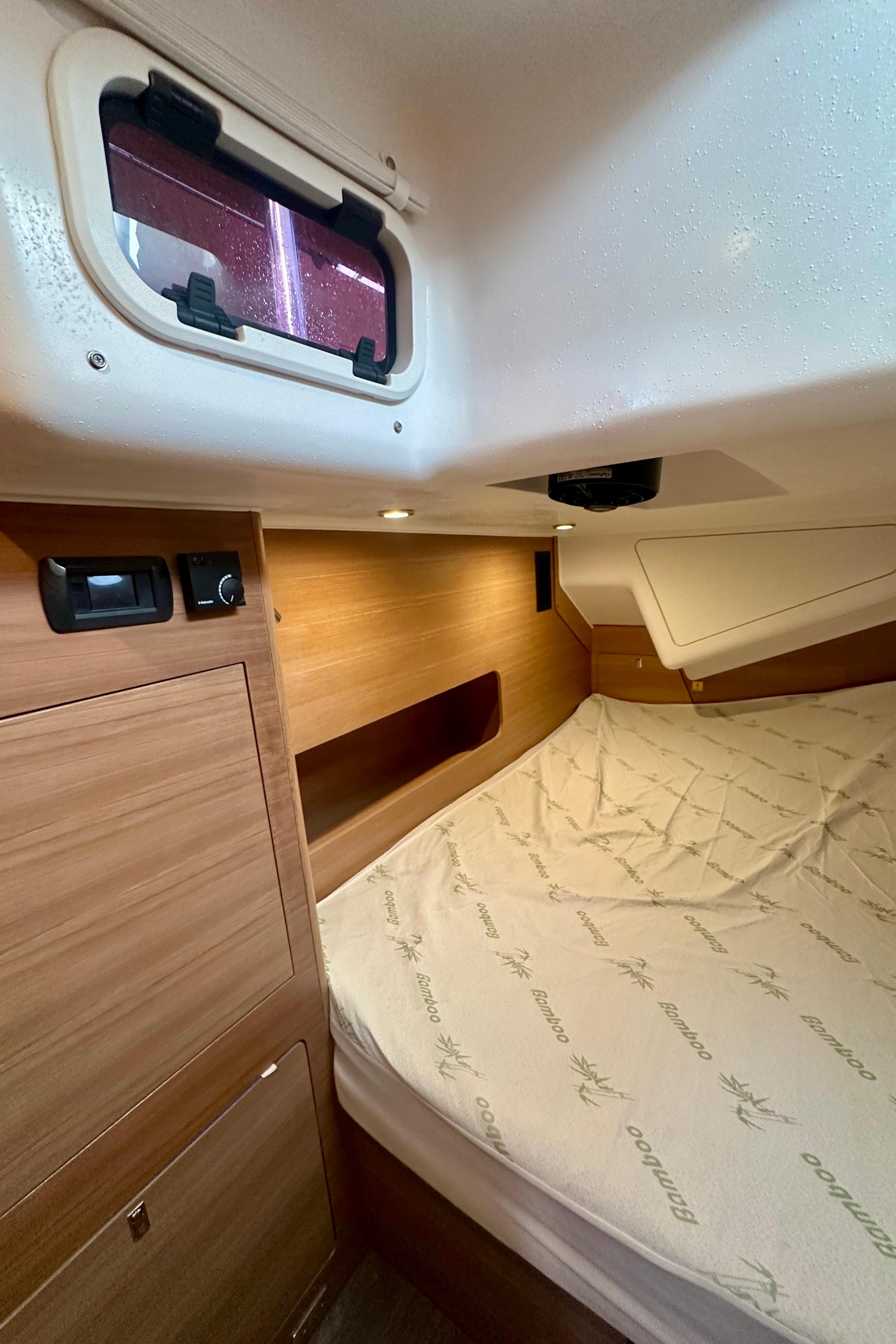2022 Elan Impression 50.1 yacht cabin with wooden interior and cozy bed.