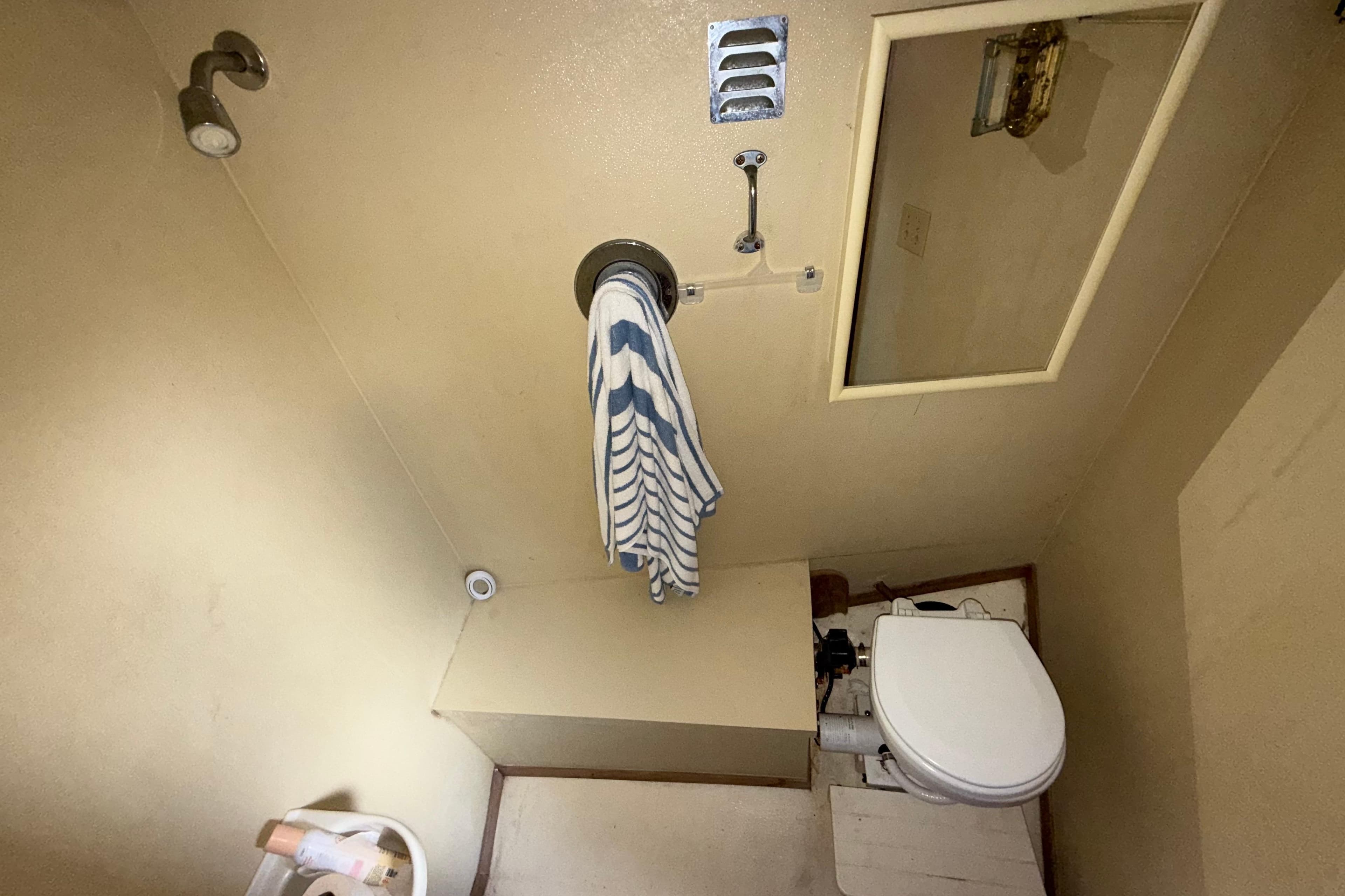 Compact bathroom with shower, toilet, and striped towel in a 1984 Custom 38 model.