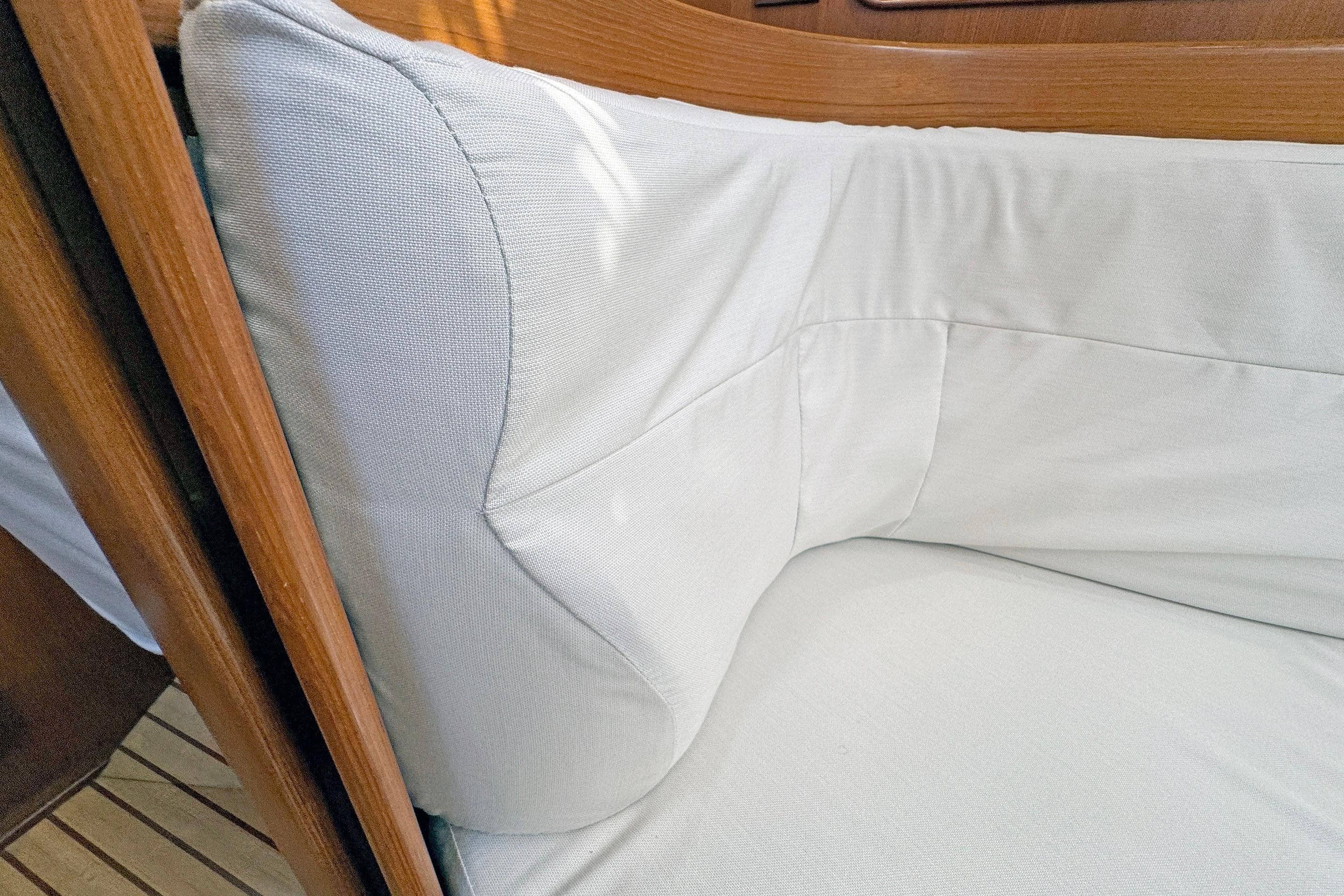 Cushioned seating area inside a 2012 Hylas 49CC yacht, featuring light upholstery and wooden trim.