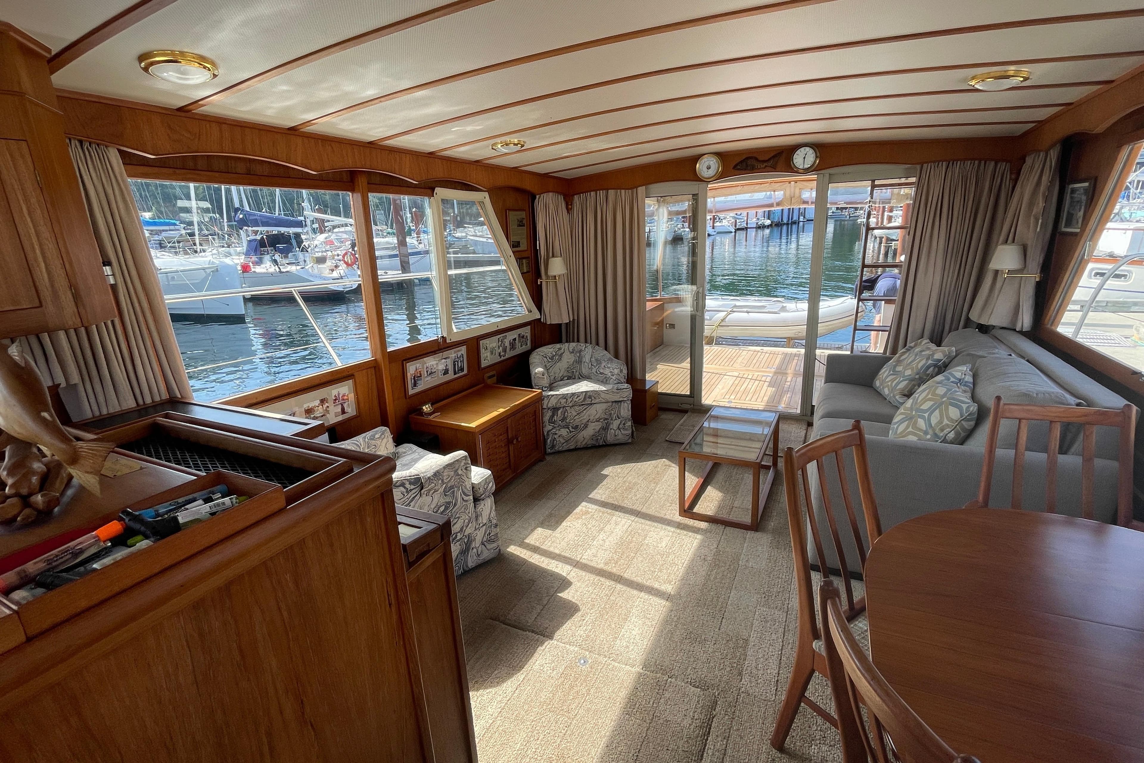 Interior of a 1979 Canoe Cove 53 yacht with wooden furnishings and marina view.