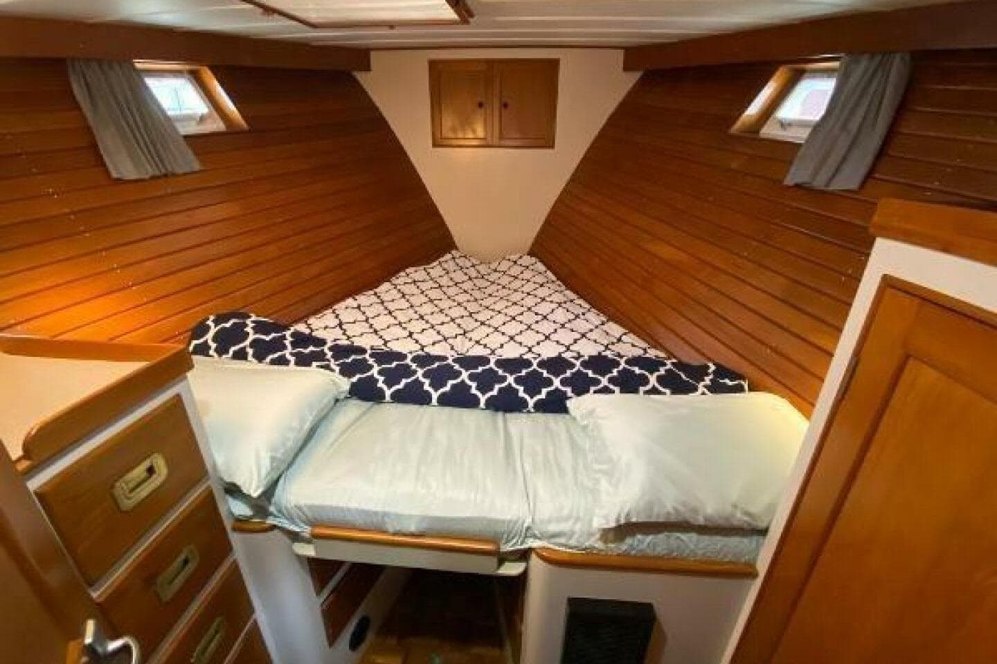Cozy cabin interior of 1973 Grand Banks 49 Alaskan with wooden paneling and bedding.