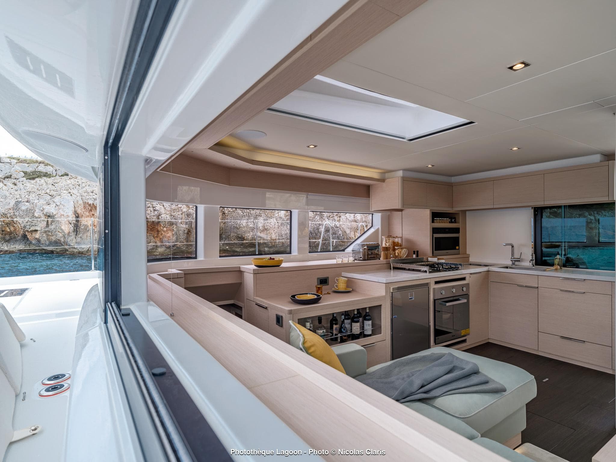 Modern interior of 2025 Lagoon 55 yacht with sleek kitchen and panoramic windows.