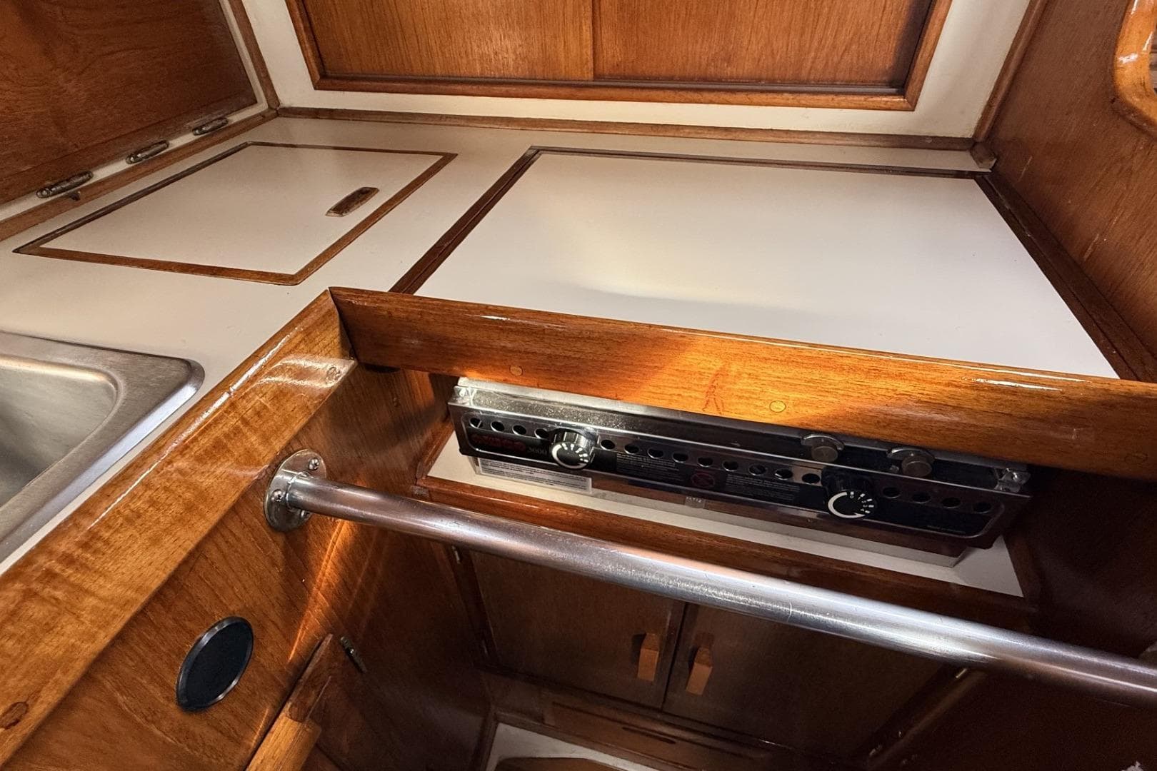 1979 Ericson 30 Plus yacht galley with wooden cabinetry and built-in stove.