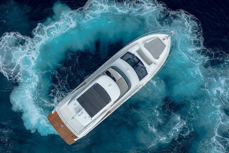 Aerial view of 2023 Absolute 62 Fly yacht navigating through vibrant blue ocean waters.