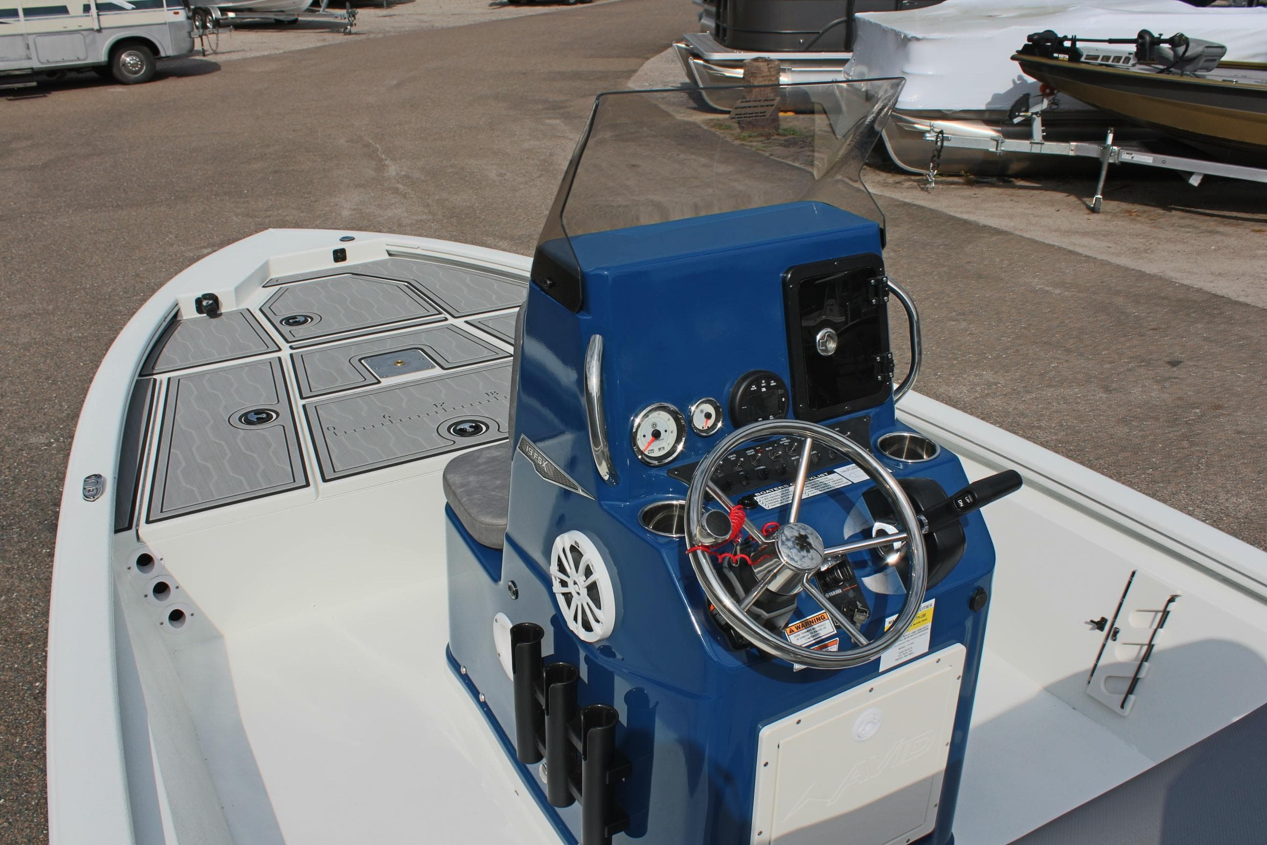 2025 Avid 19 FSX boat with blue console and steering wheel, docked outdoors.
