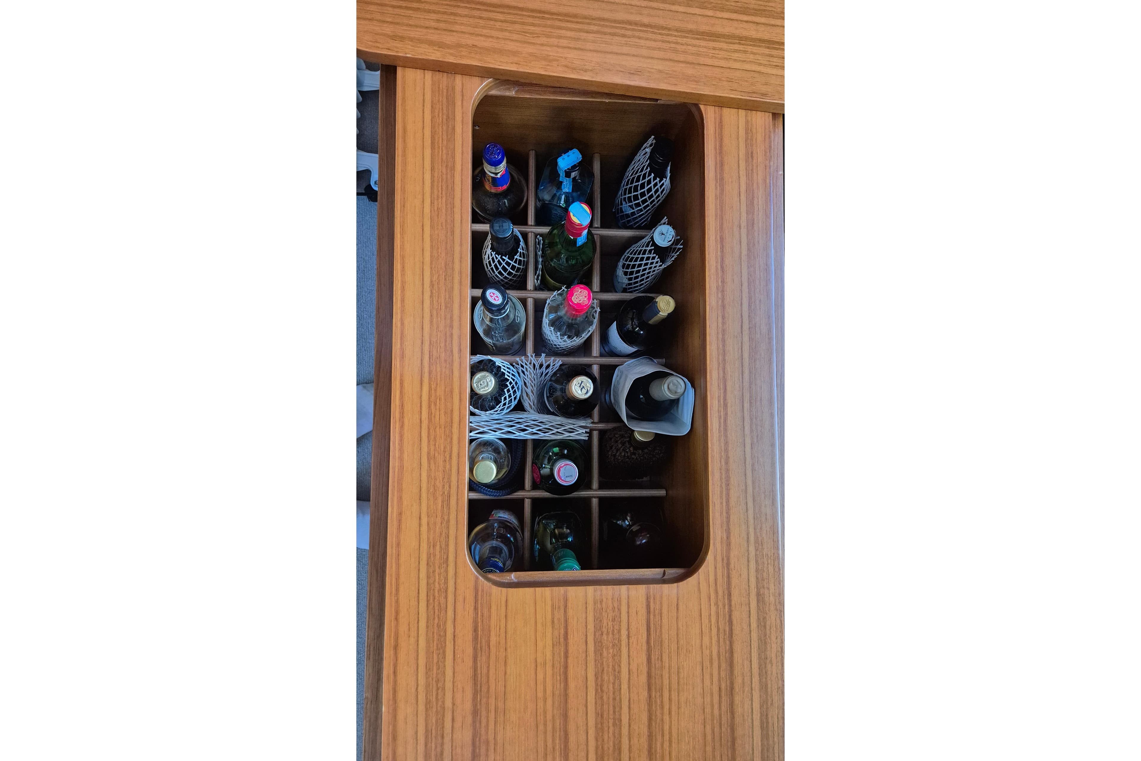 Built-in wine storage on 2013 Hallberg-Rassy 55 yacht, featuring wooden compartments.