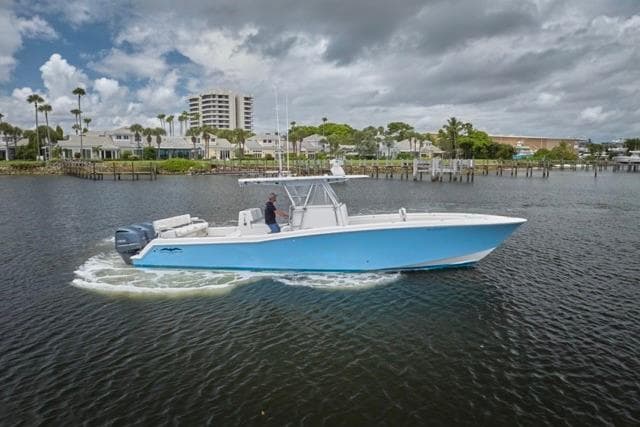 Invincible 36 boat cruising on water, 2015 model, with scenic coastal backdrop.