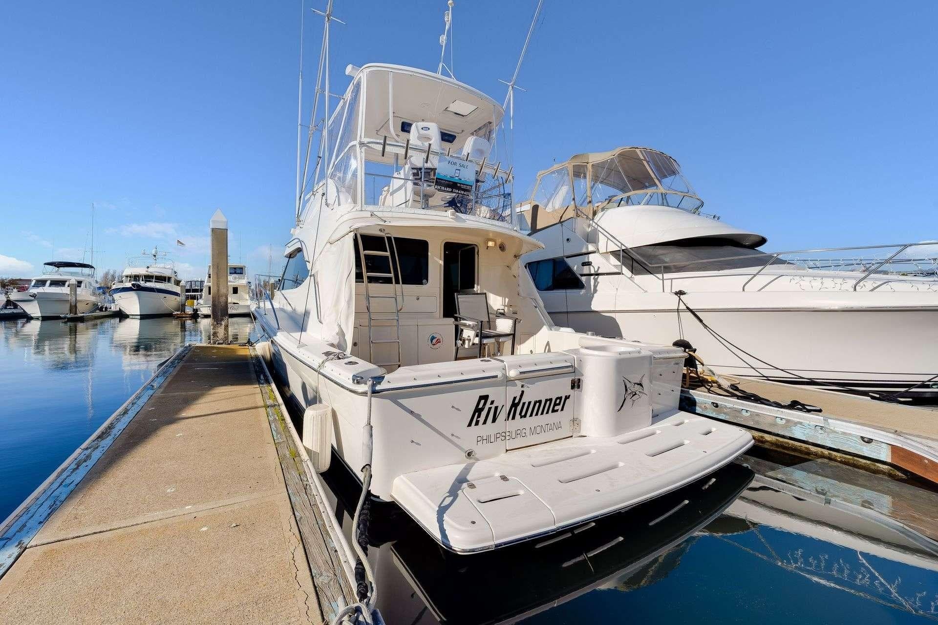 2004 Riviera Convertible yacht docked at marina under clear blue sky.