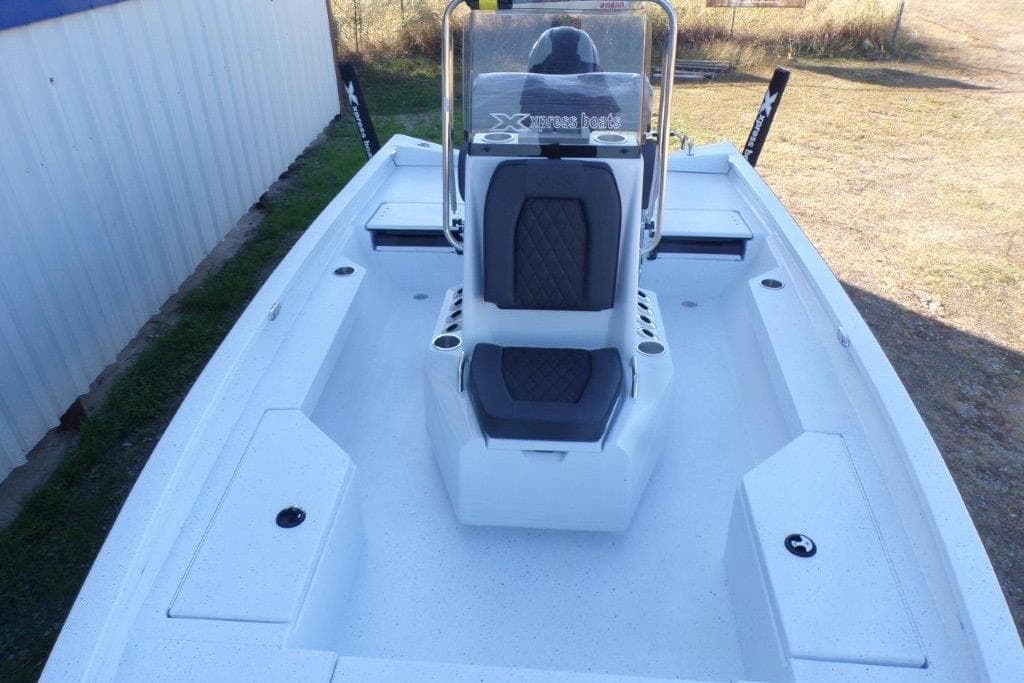 2026 Xpress H20B Bay boat interior with seating and console, parked outdoors.