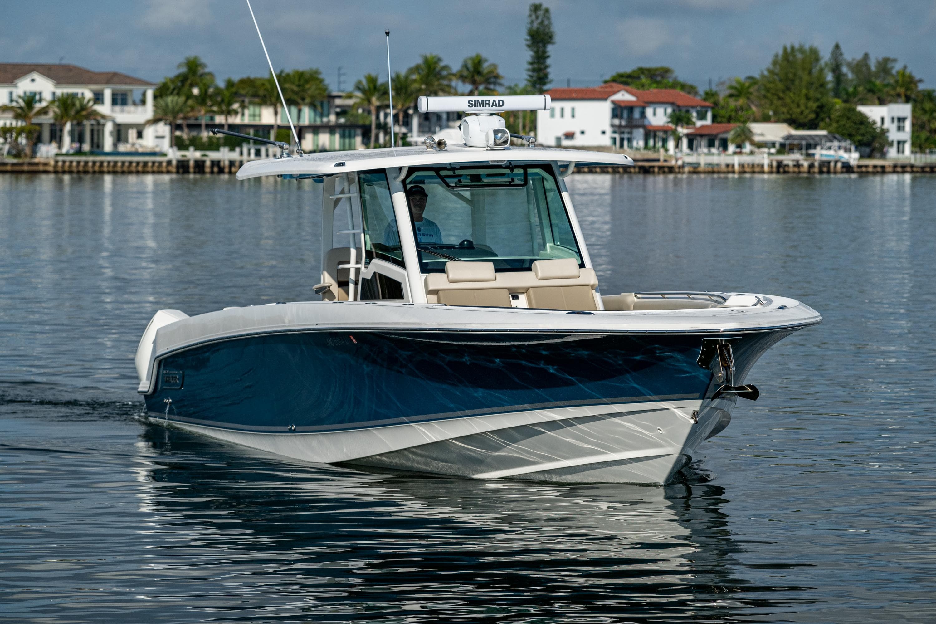 2024 Boston Whaler 380 Outrage boat cruising on calm water near waterfront homes.