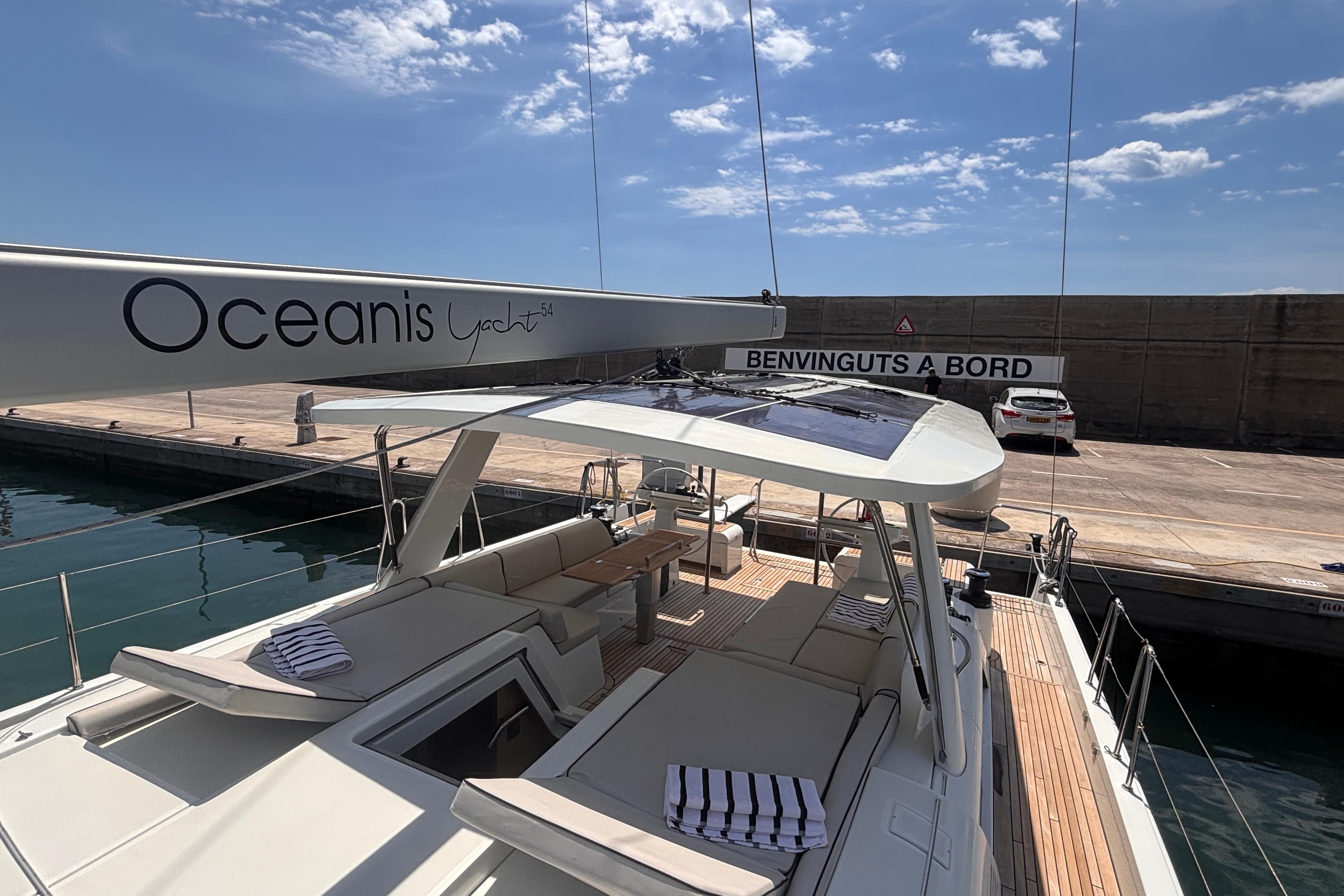 2020 Beneteau Oceanis Yacht 54 docked, showcasing elegant deck and seating area under clear sky.