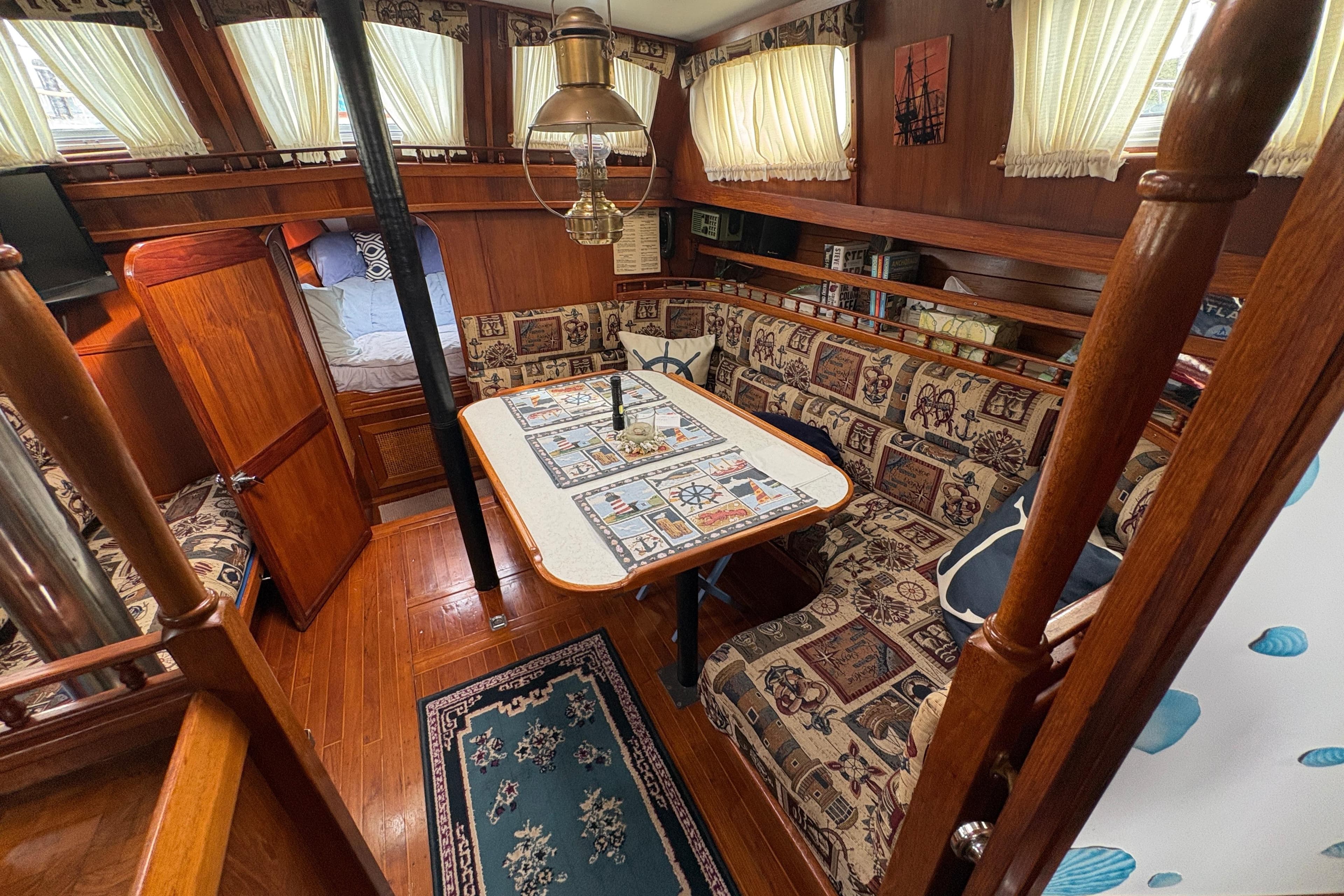 Interior of 1977 Folkes Full Keel Offshore Cutter with cozy seating and nautical decor.